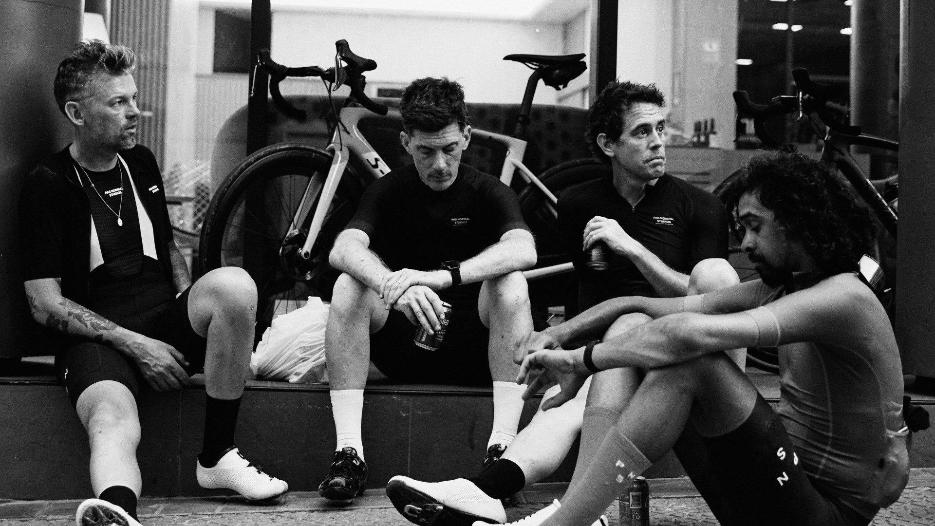 Cyclists in black jerseys resting in garage with bikes after training session