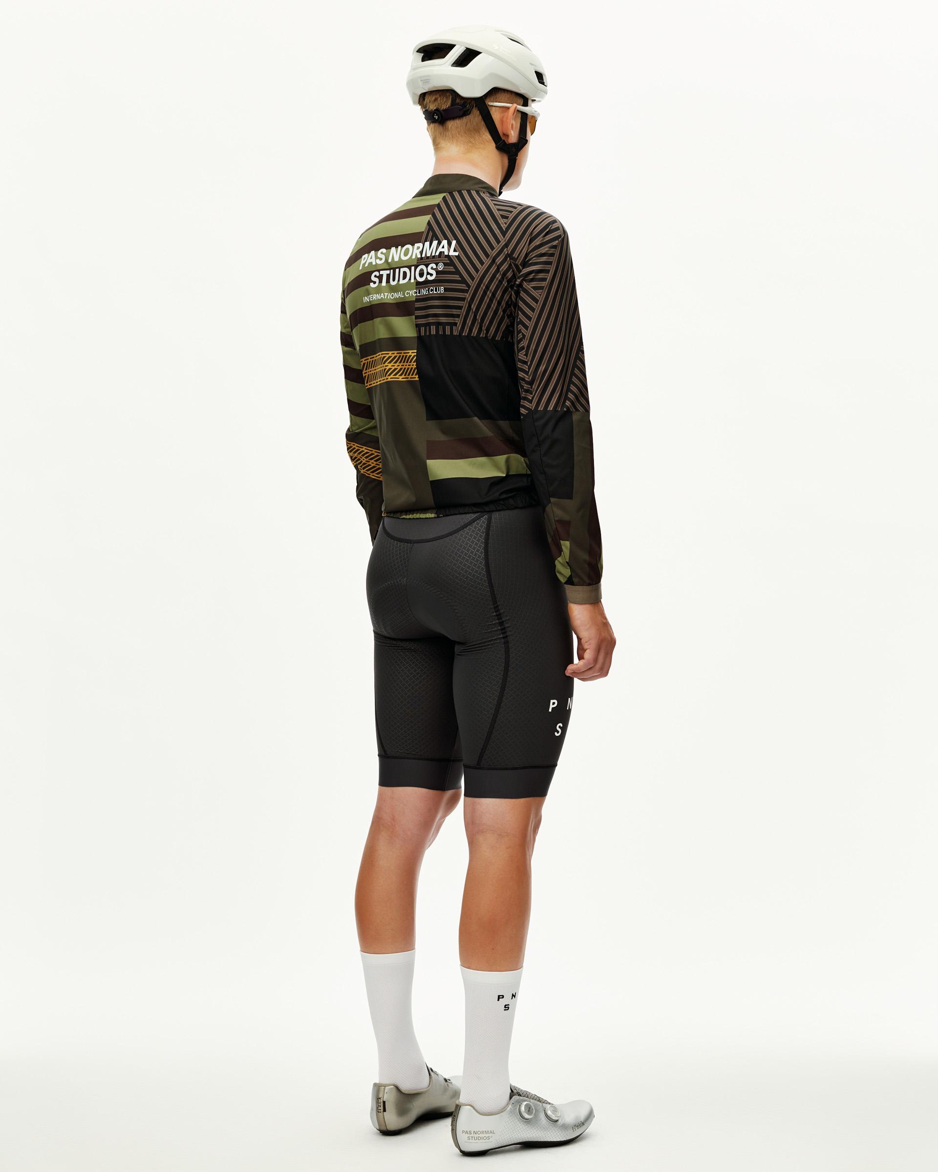 International Green Mechanism Stow Away cycling jacket on model, rear view with geometric patchwork print