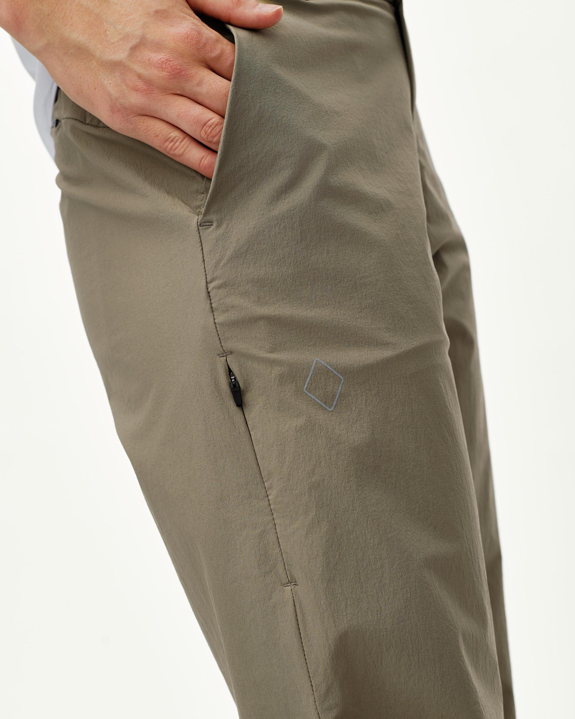 Dusty Earth khaki Off-Race Tech women's pants, side detail on model with zip thigh pocket and diamond logo