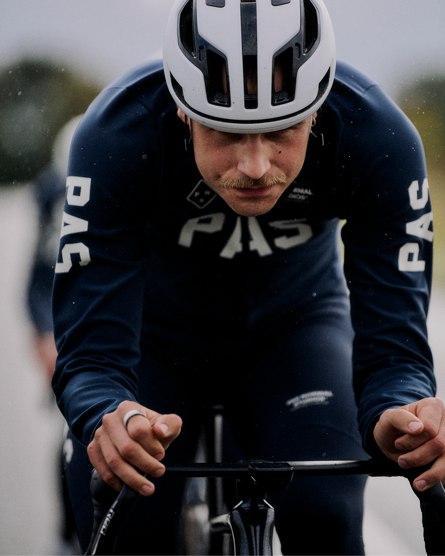 Model wearing Men's PAS collection navy time trial suit with white helmet in aerodynamic position