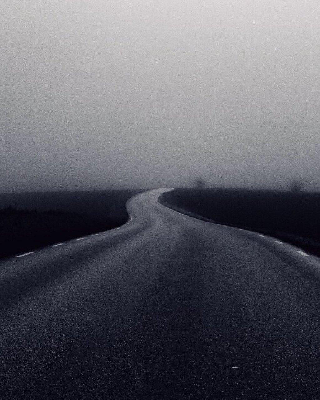 Empty road curving through misty landscape