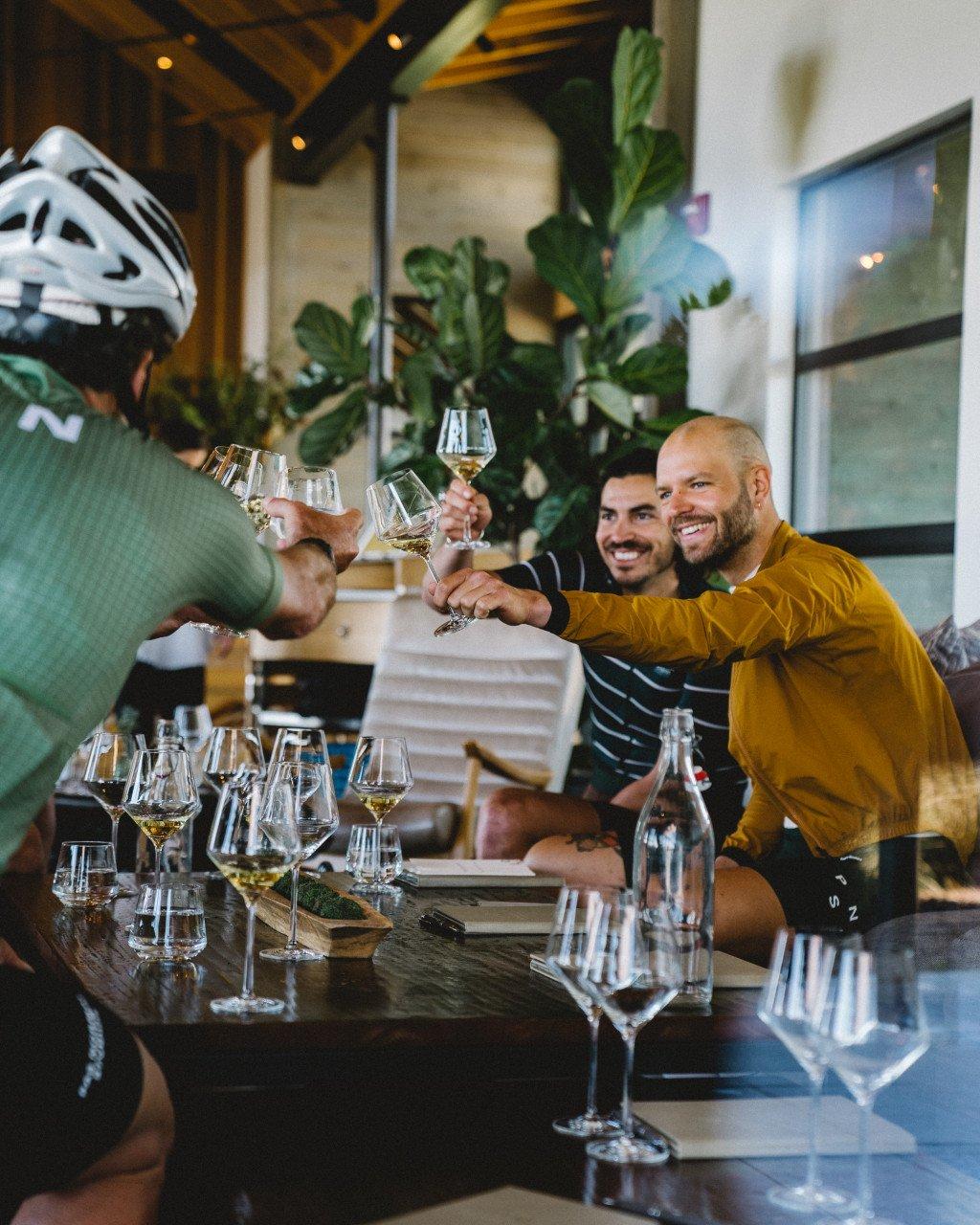 Cyclists celebrating with wine glasses at restaurant table after ride in Sonoma