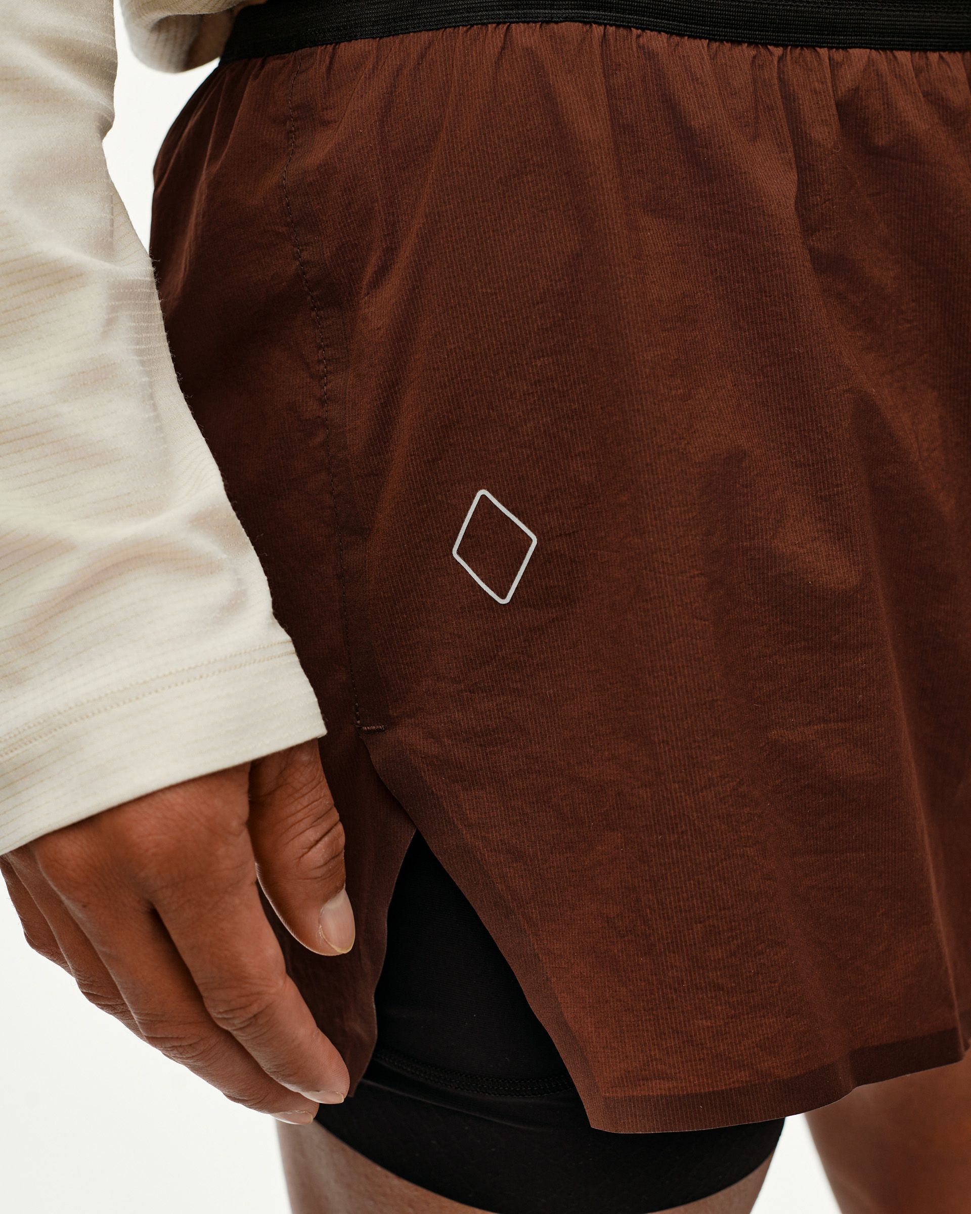 Maroon Brown Balance 2-in-1 shorts, side detail on model with diamond logo print and black inner layer visible
