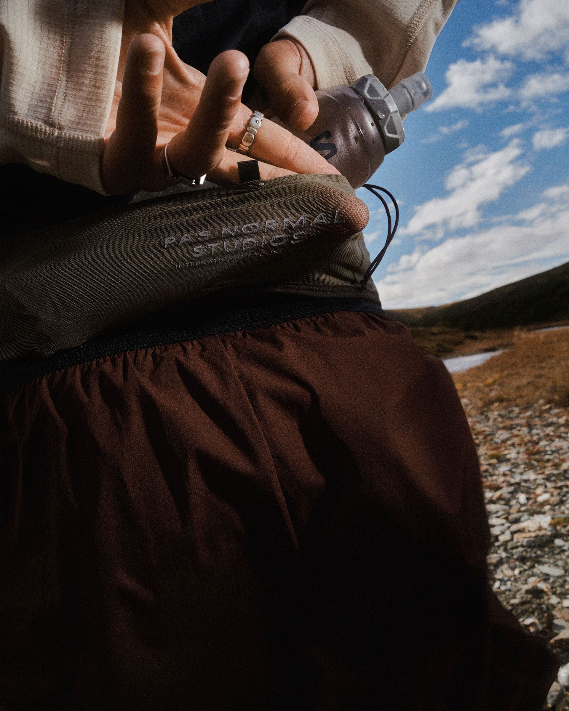 Light Brown Salomon S/LAB Belt on model, detail view showing embossed logo and elastic waistband with Salomon flask