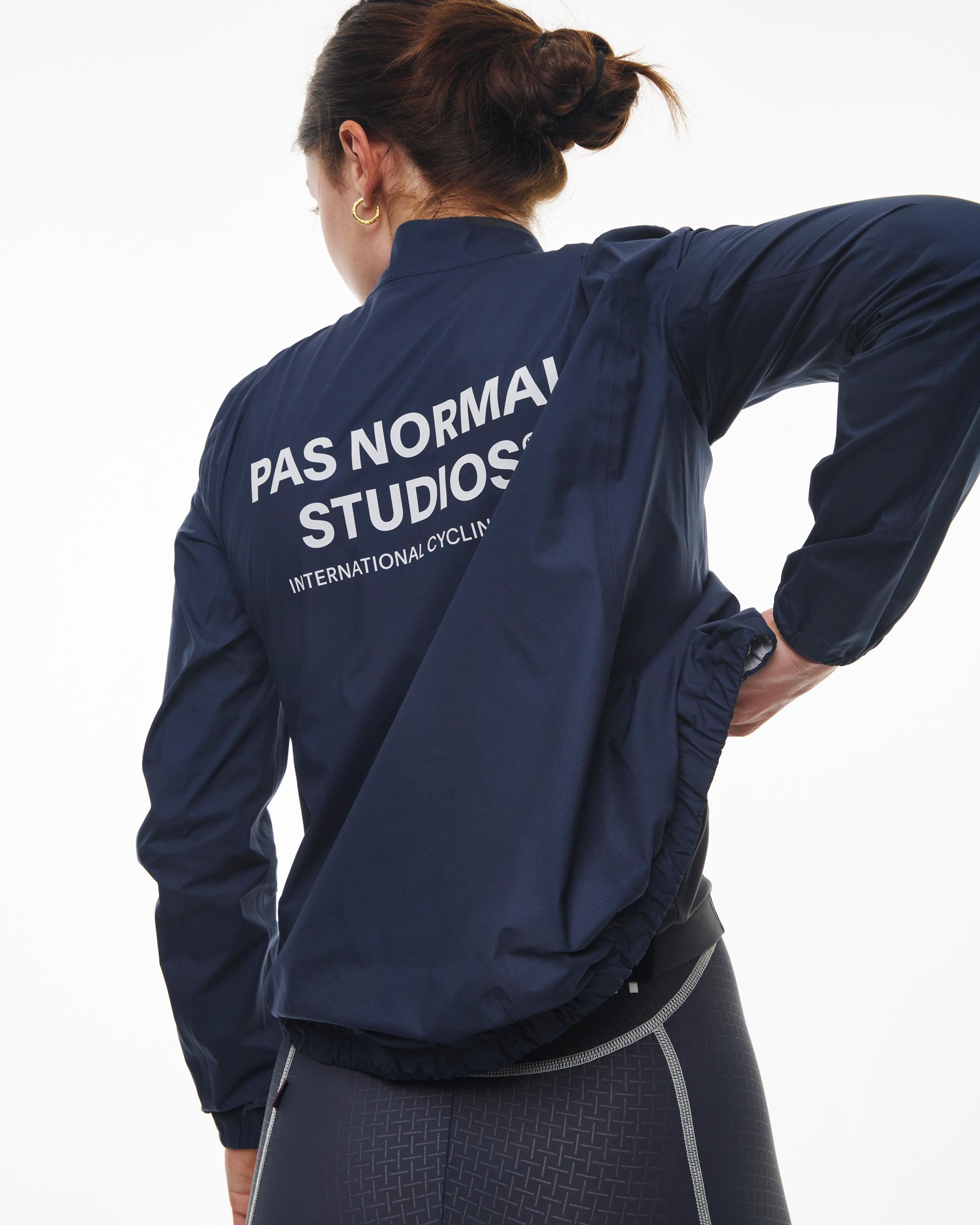 Navy Mechanism Pertex Rain cycling jacket on model, rear view with white logo print