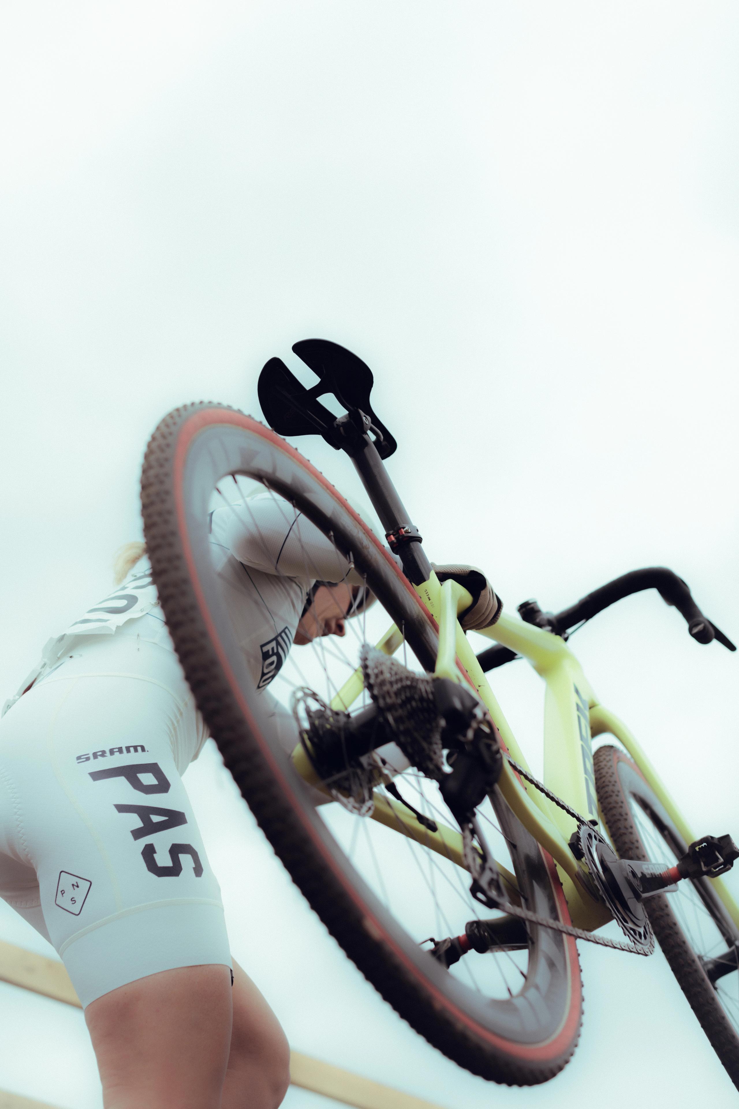 Model wearing white cycling jersey in aerodynamic position on yellow time trial bike