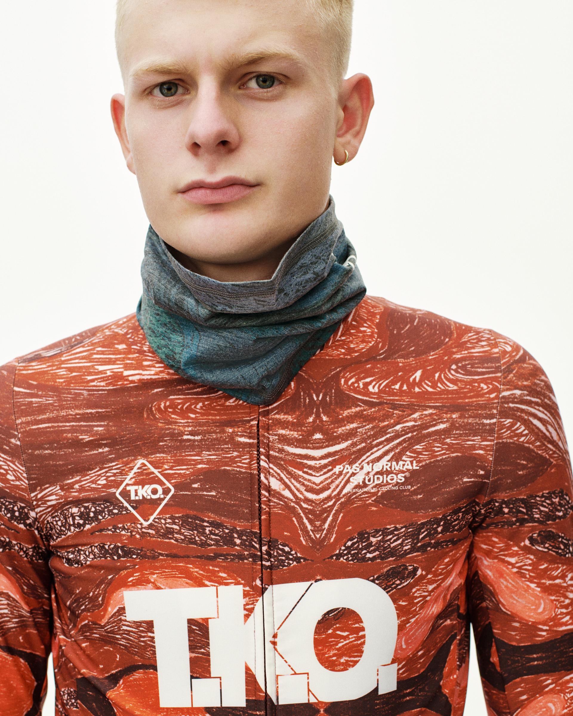 Dark Multi T.K.O. Merino necktube on model, front view worn around neck over red all-over print jersey