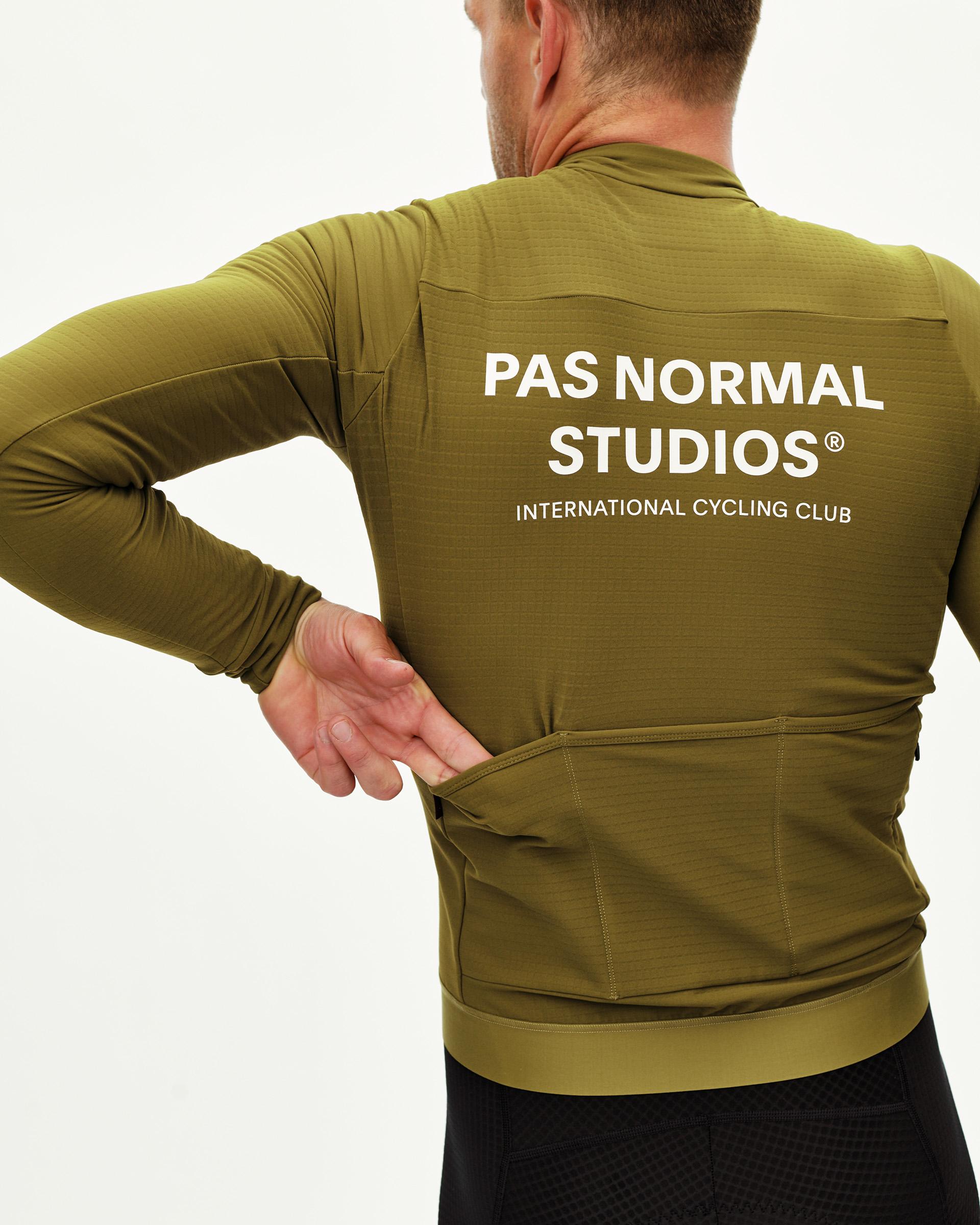 Khaki Green Essential long sleeve cycling jersey on model, rear view with white back print and rear pockets