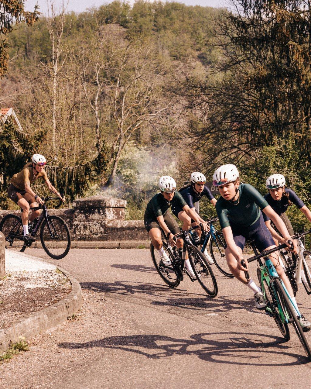 Cyclists in dark aerodynamic suits racing on rural road in formation