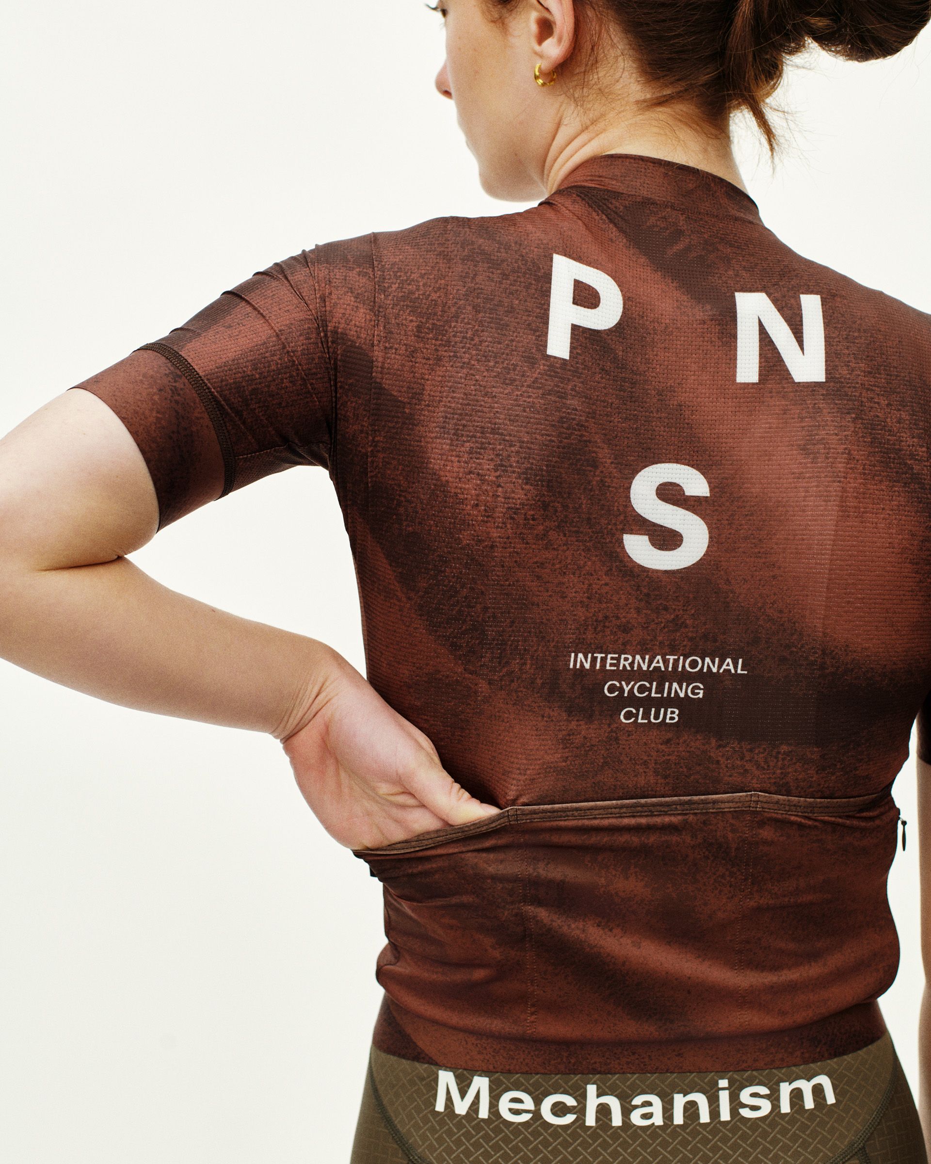 Brown Mechanism cycling jersey on model, rear view with white PNS logo and International Cycling Club text