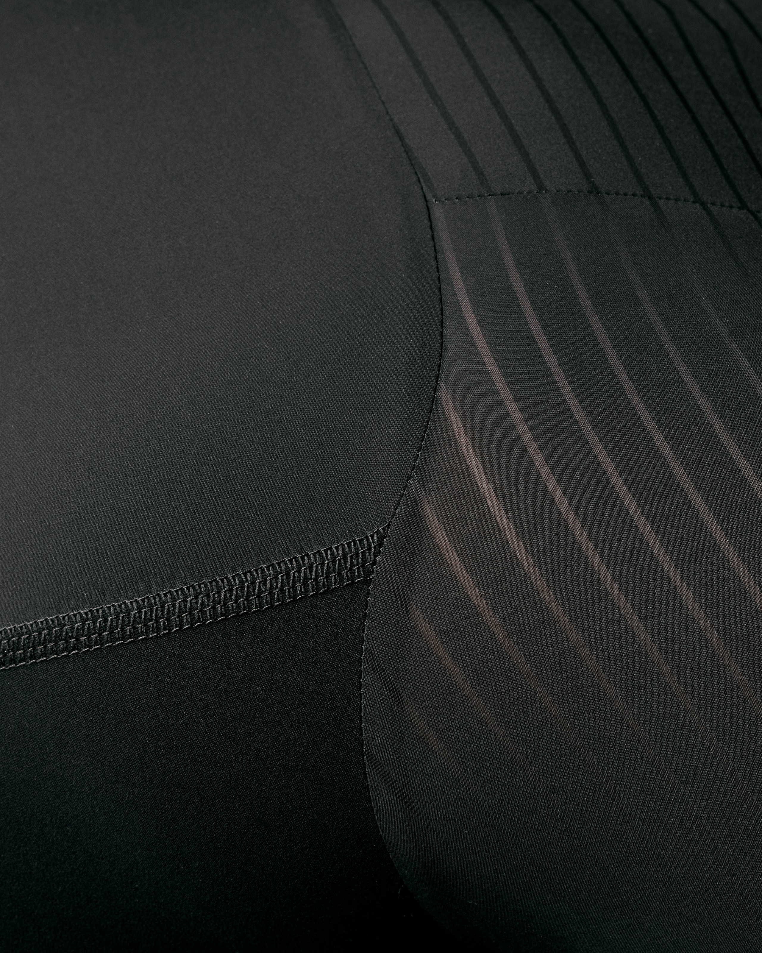 Brown PAS Mechanism Pro speedsuit detail view showing ribbed panels and contrast stitching