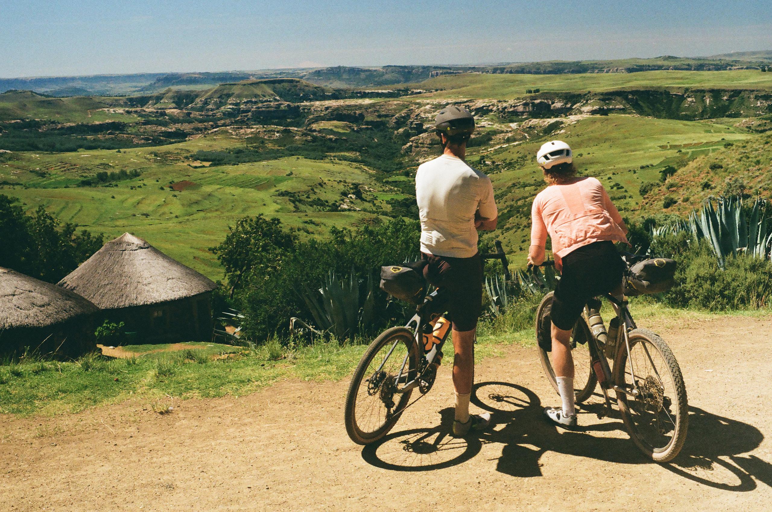 Two cyclists with gravel bikes overlooking rolling hills and valleys in rural landscape