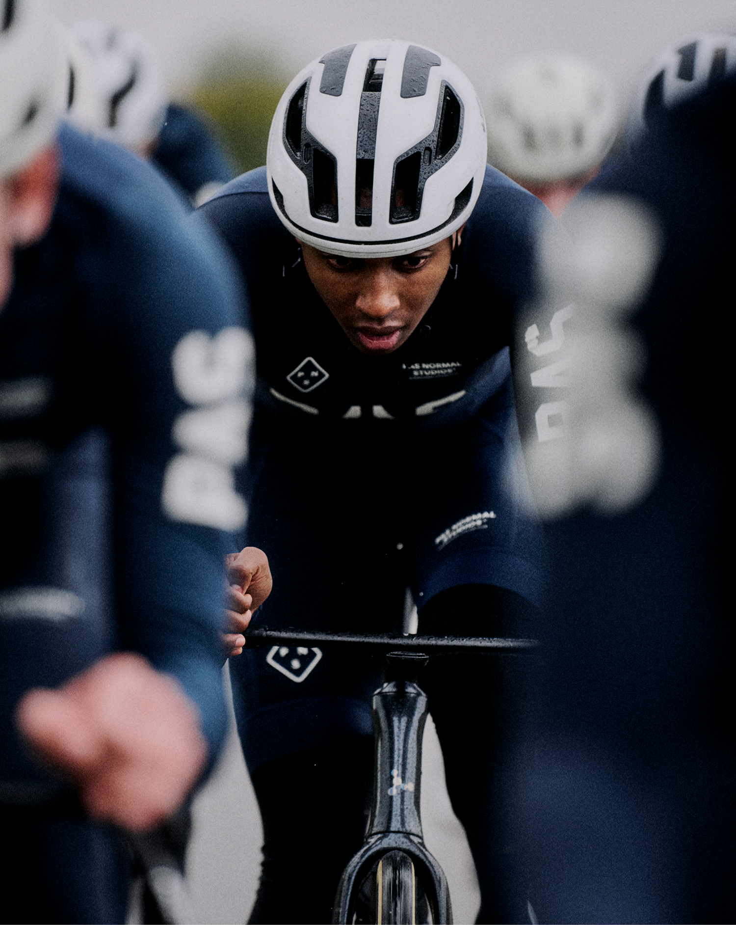 Model wearing black PAS Autumn/Winter 2025 time trial suit with white helmet in aerodynamic position