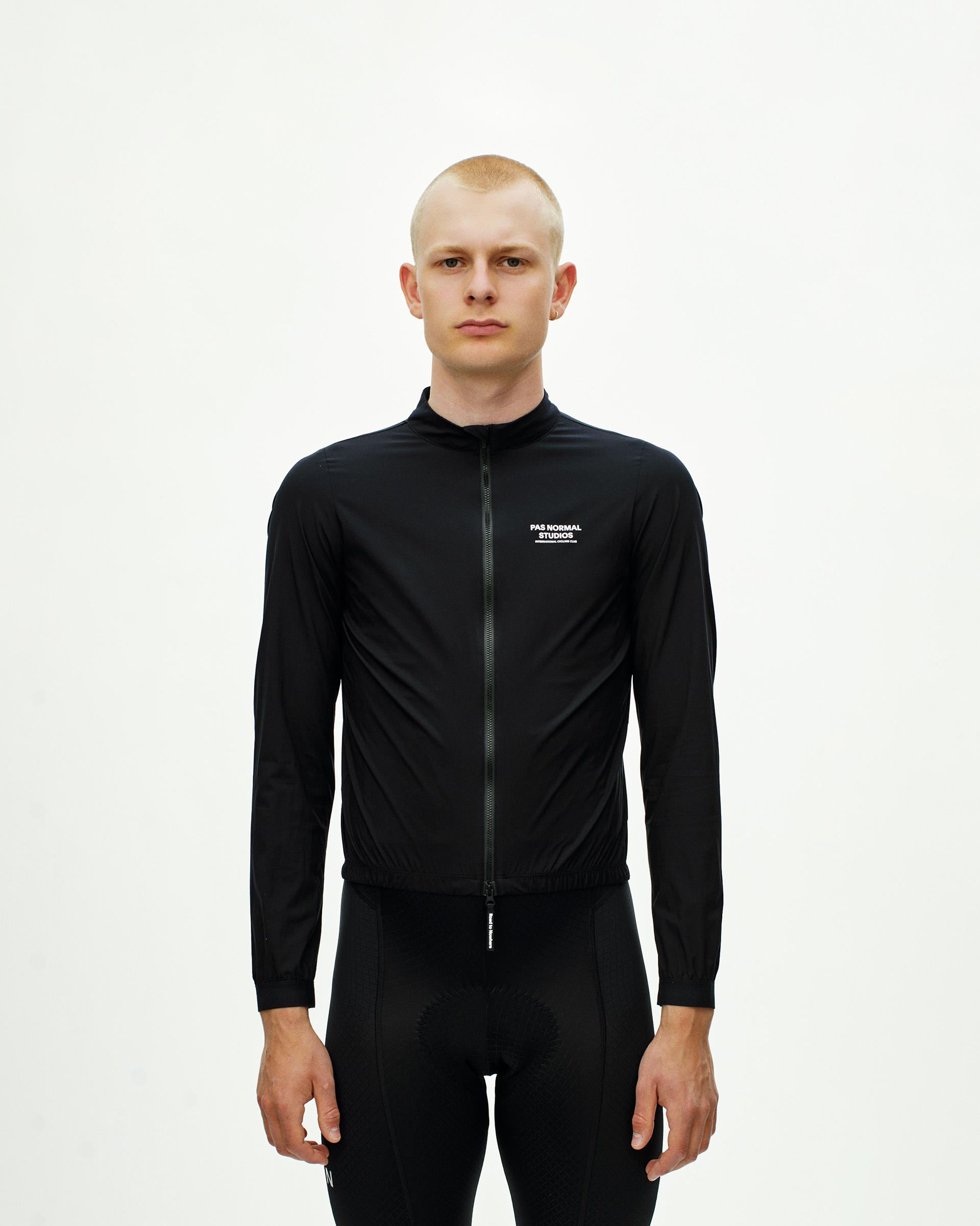 Black Mechanism Stow Away cycling jacket on model, front view with full zip and white chest logo print