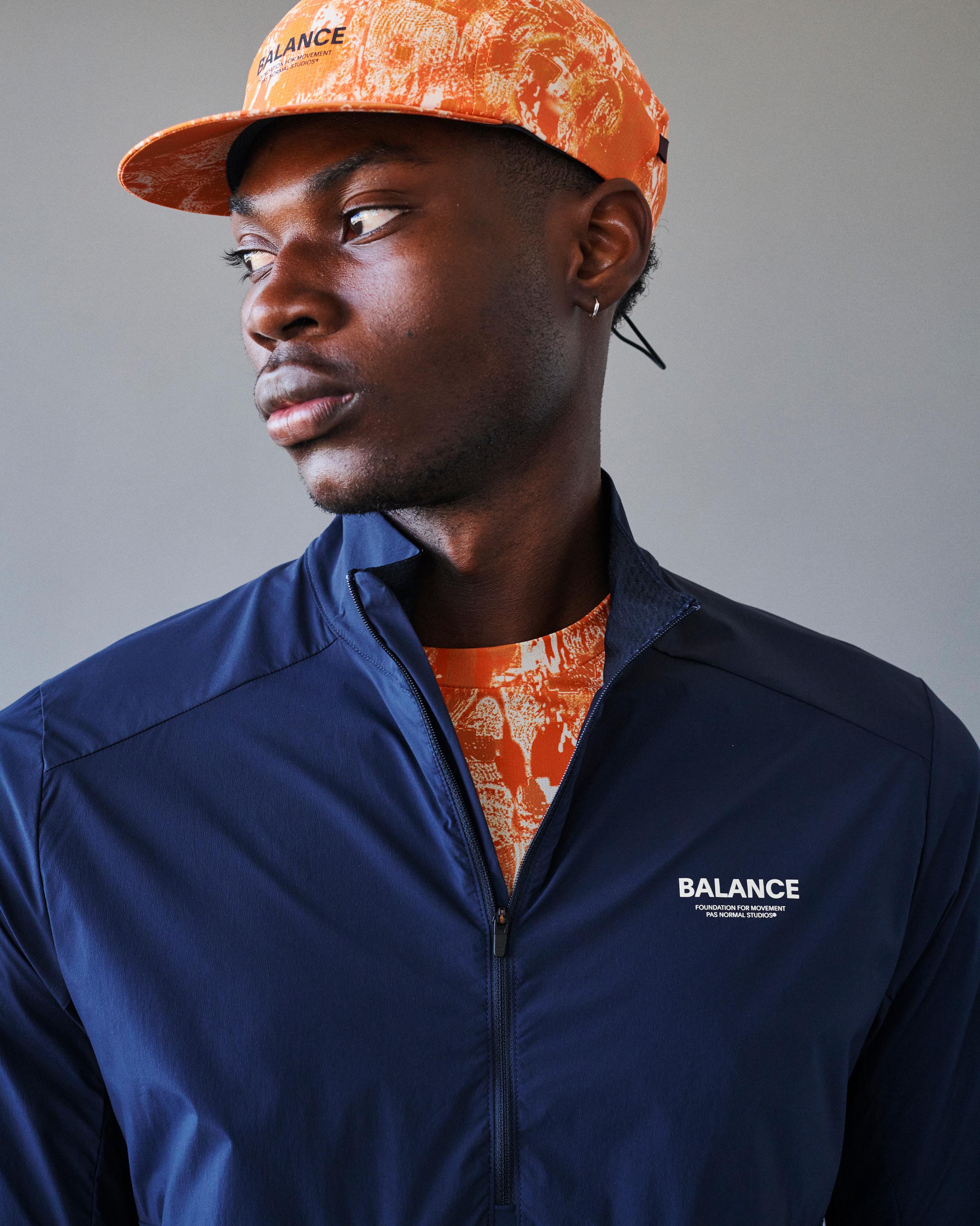 Orange Balance cap on model, three-quarter front view with abstract all-over print and front logo text
