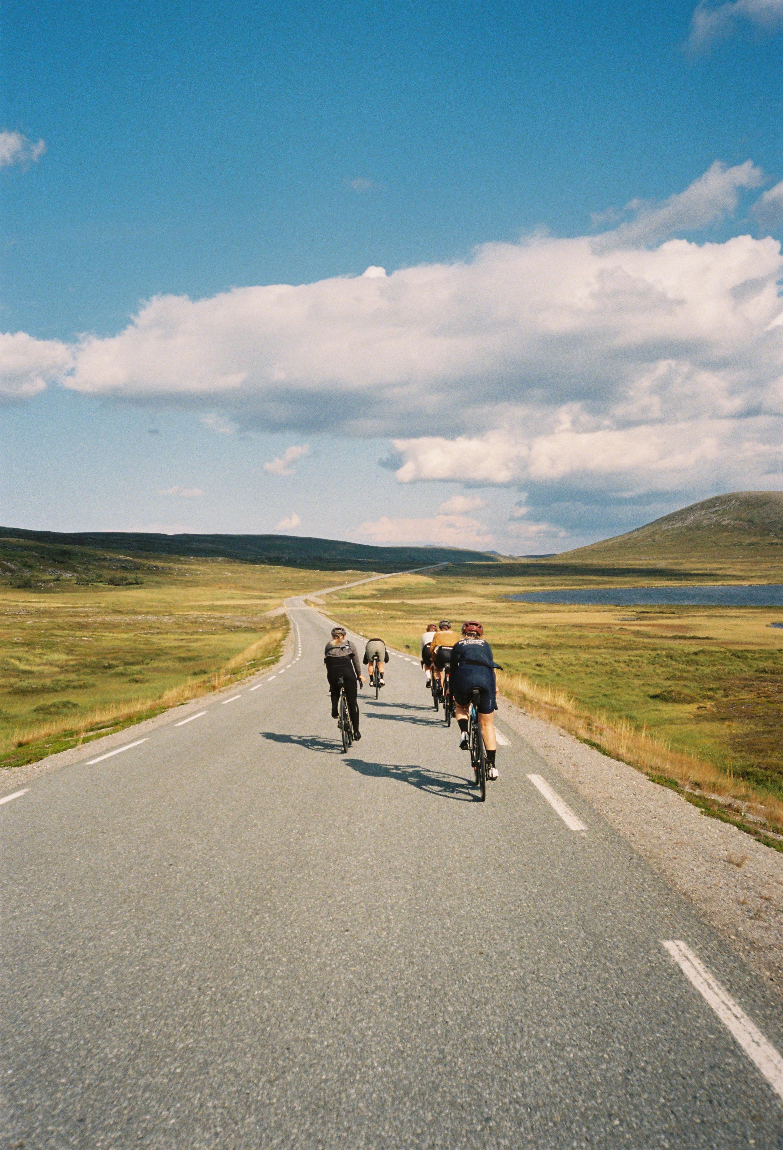 Group of cyclists riding on remote mountain road through scenic highland landscape