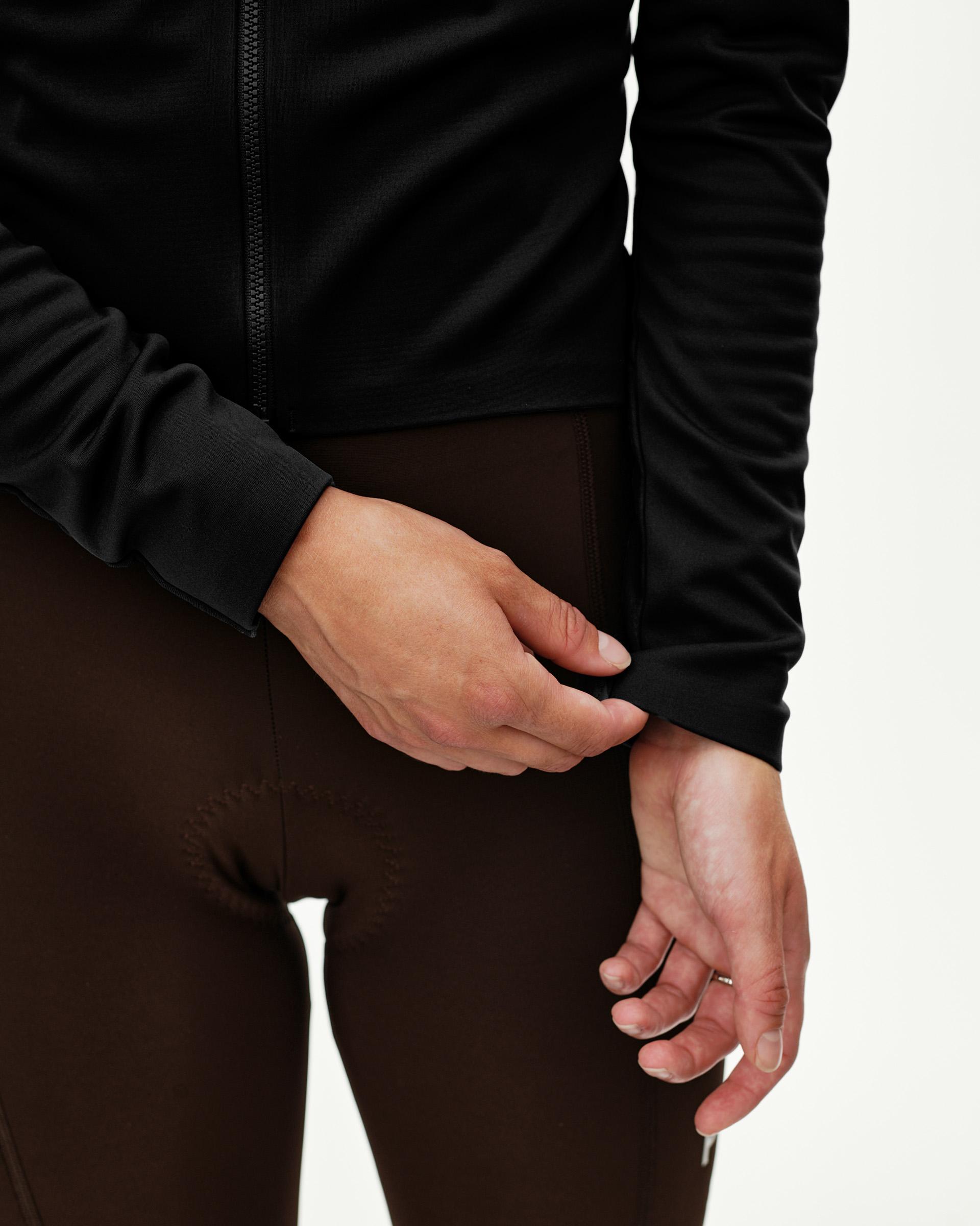 Black Mechanism Thermal Long Sleeve cycling jersey on model, front detail view with zip and fitted cuff