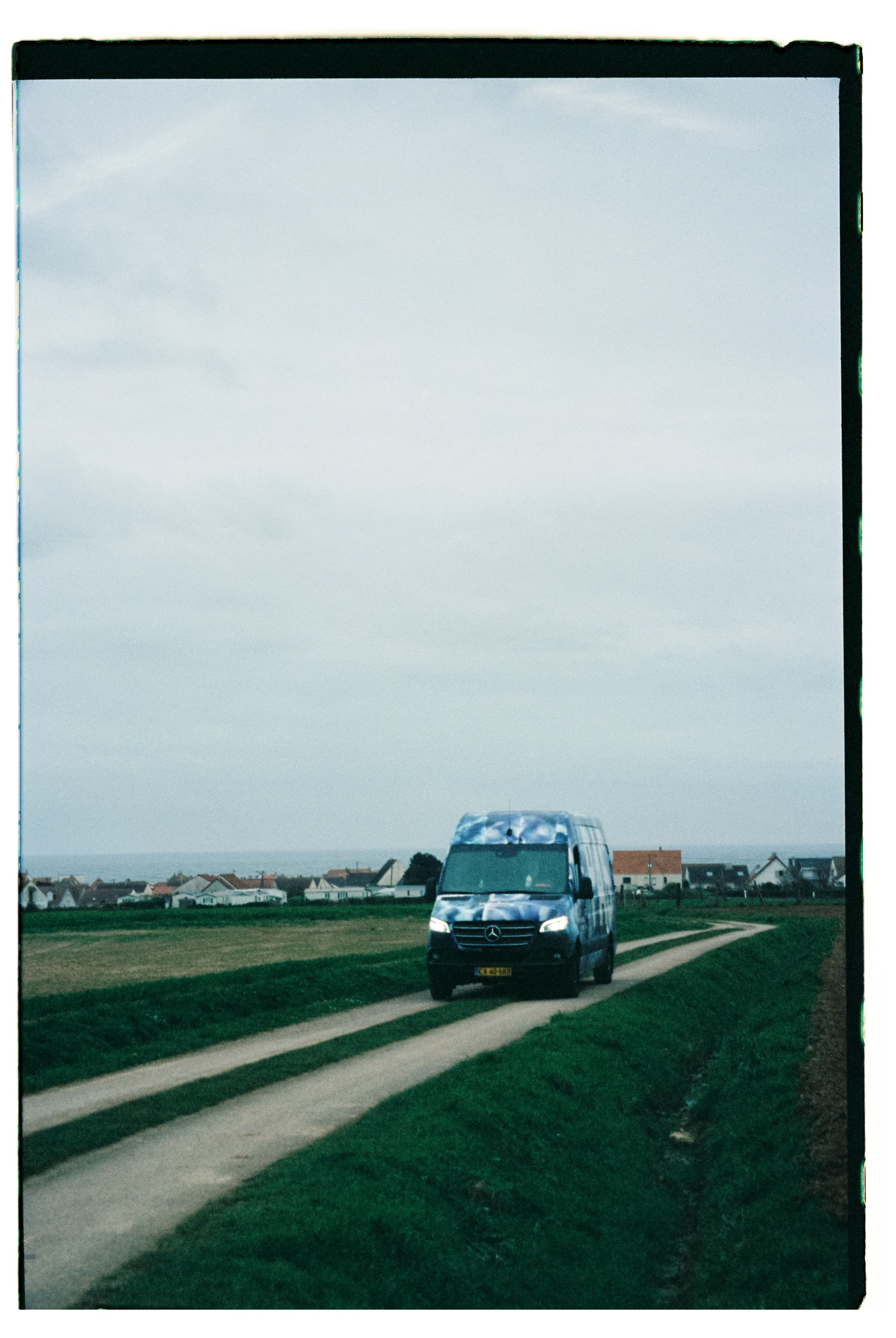 Mercedes van driving on rural road through countryside with houses in distance