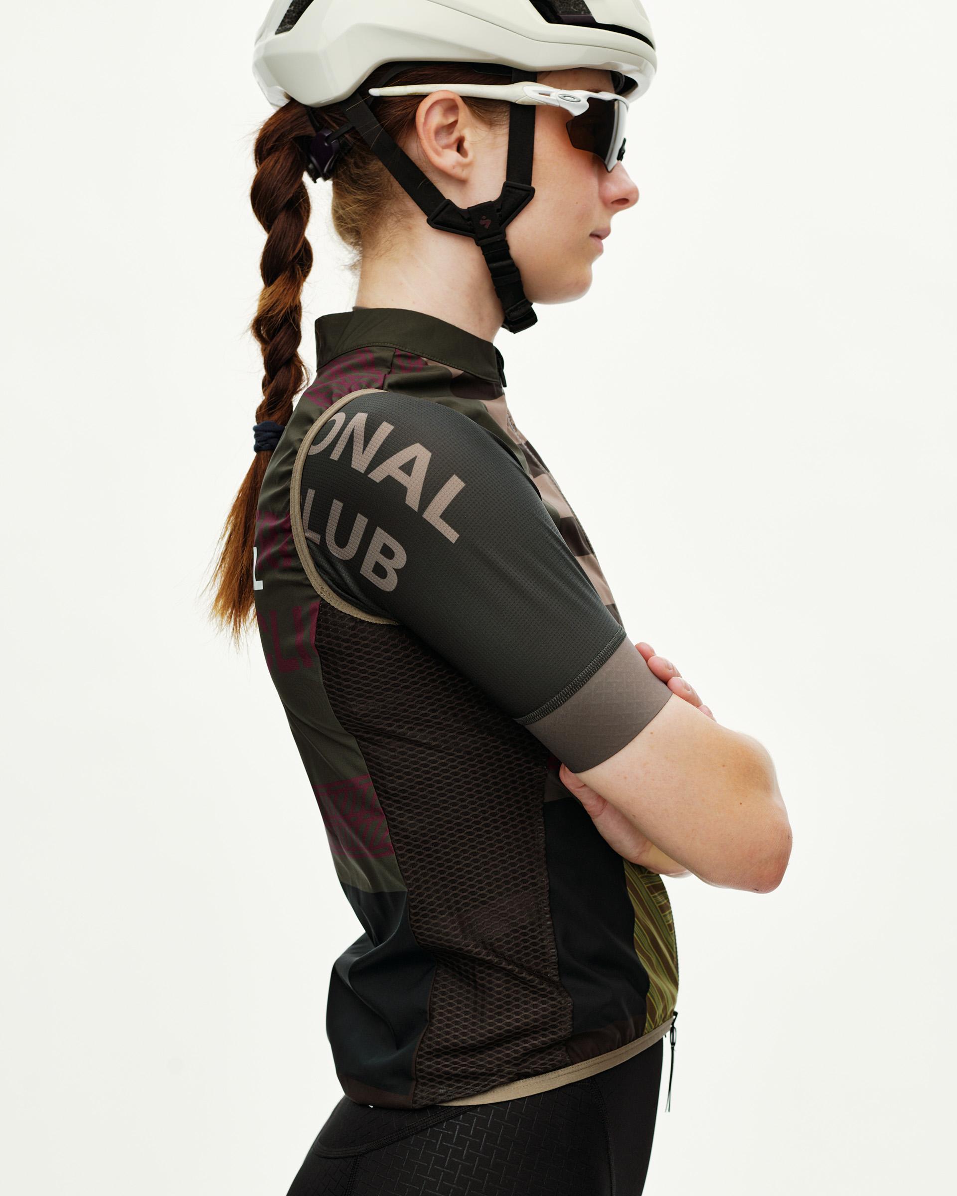Dusty Earth khaki Mechanism Stow Away women's cycling gilet, side view on model with graphic sleeve print