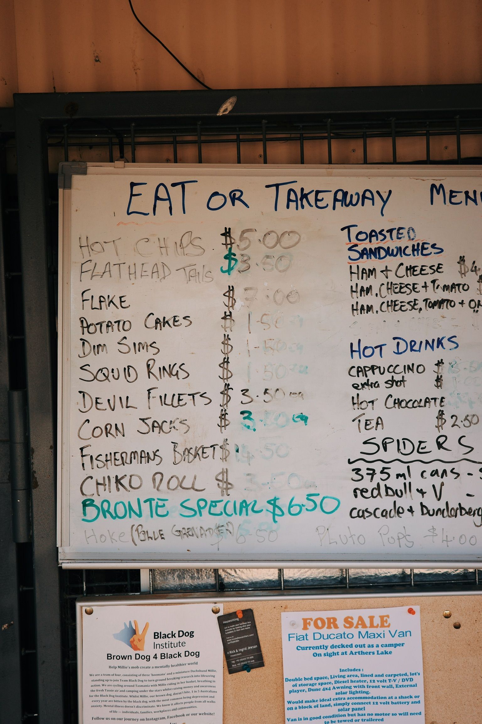 Restaurant menu board showing eat-in and takeaway options with fish and chips, sandwiches, and hot drinks