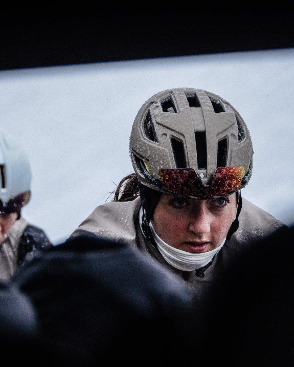 Cyclist wearing grey helmet with tinted goggles in snowy conditions, water droplets on face
