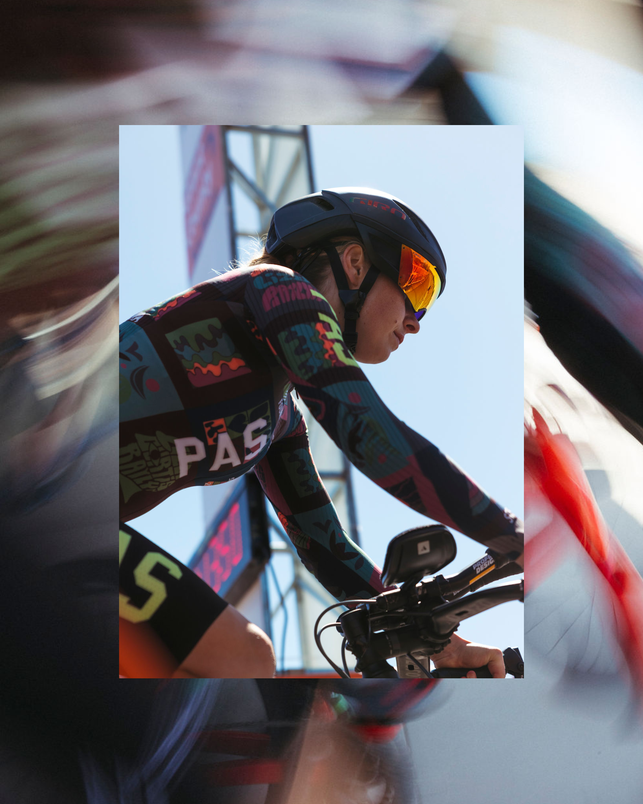 Model wearing PAS Collection time trial suit with colorful geometric pattern in aerodynamic racing position