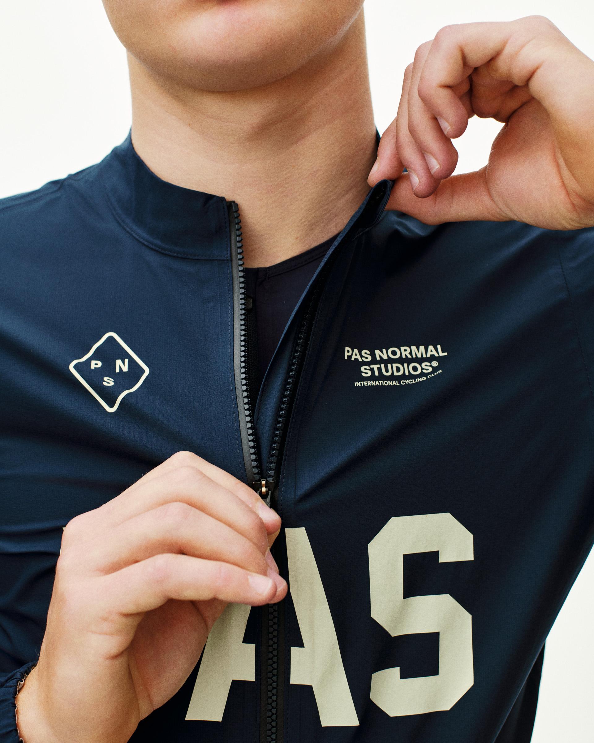 Navy PAS Mechanism Rain cycling jacket on model with quarter zip and cream chest print