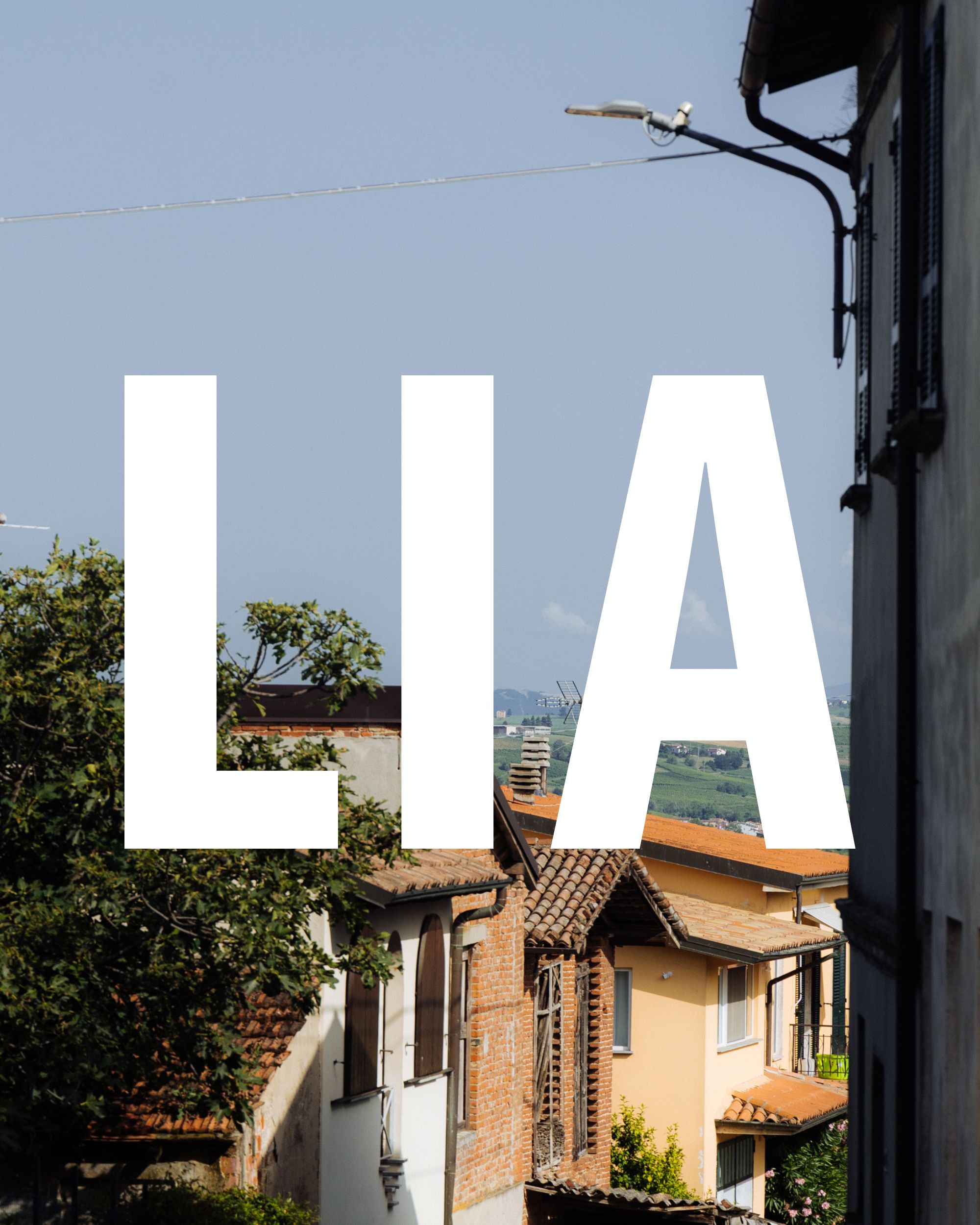 Italian village rooftops with large white "LIA" text overlay