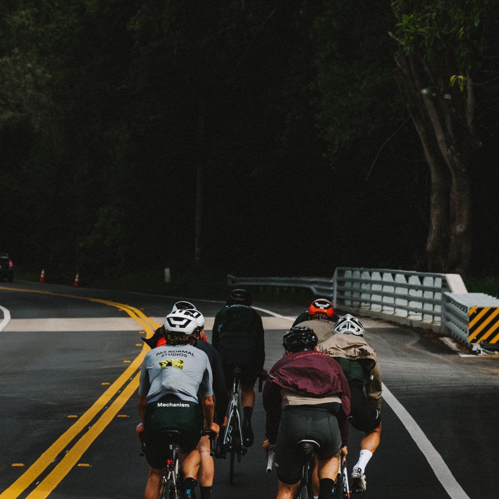 Group of cyclists riding on mountain road including rider wearing Mechanism jersey