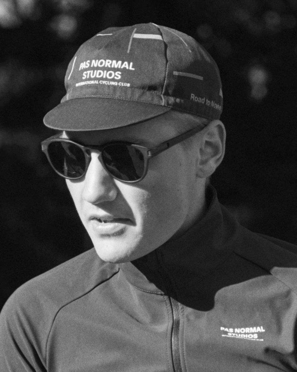 Model wearing cycling cap with logo and sunglasses in black and white portrait