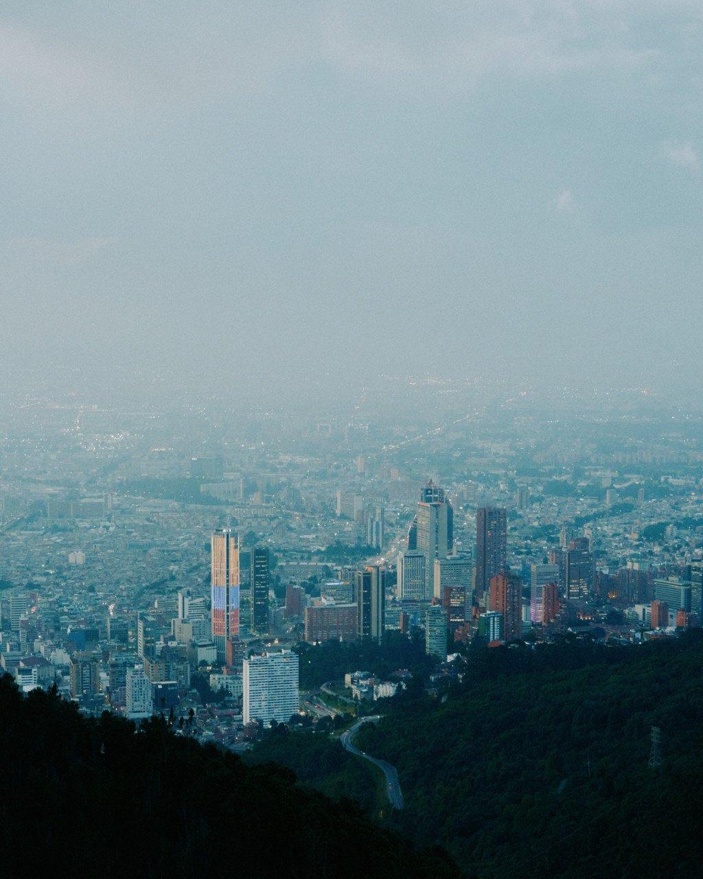 Aerial view of Bogotá cityscape with downtown skyscrapers emerging from misty valley surrounded by mountains