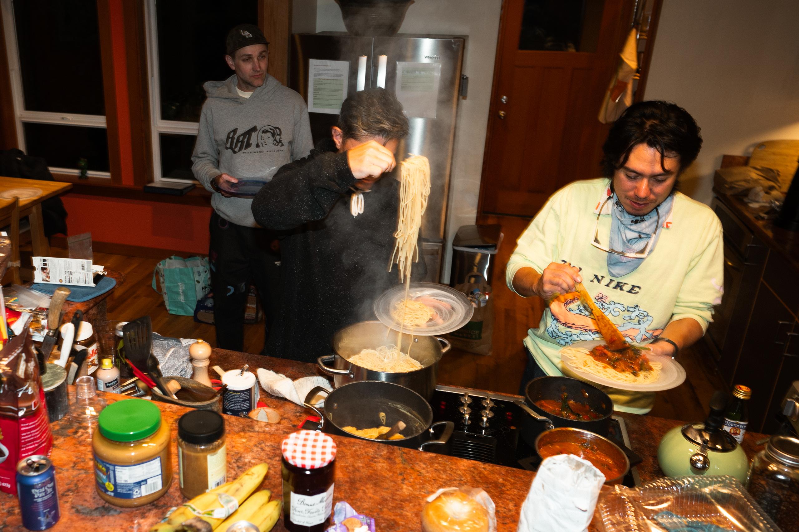 Team members preparing pasta meal in kitchen during training camp
