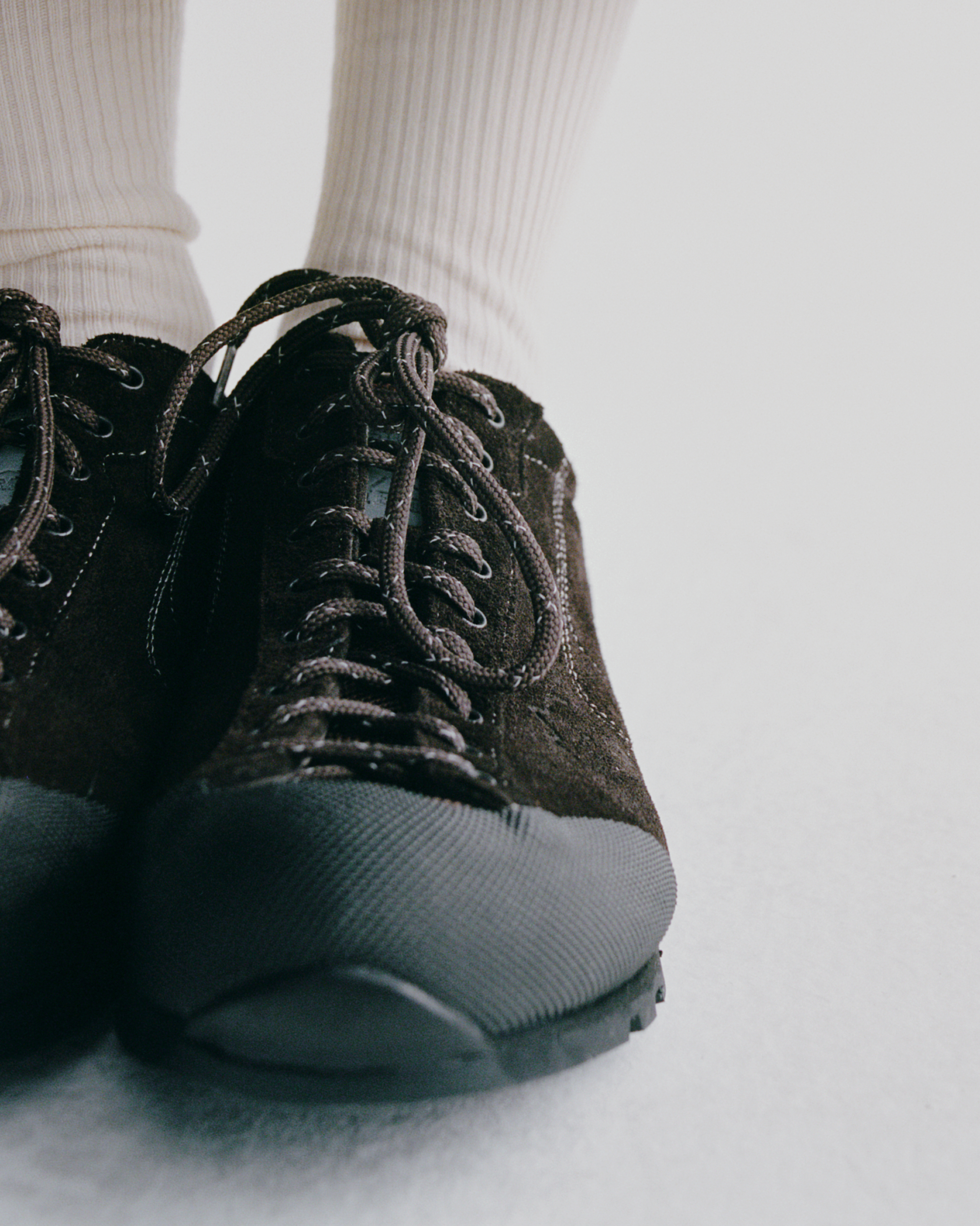Black suede cycling shoes with lace-up closure and textured sole, worn with white ribbed socks