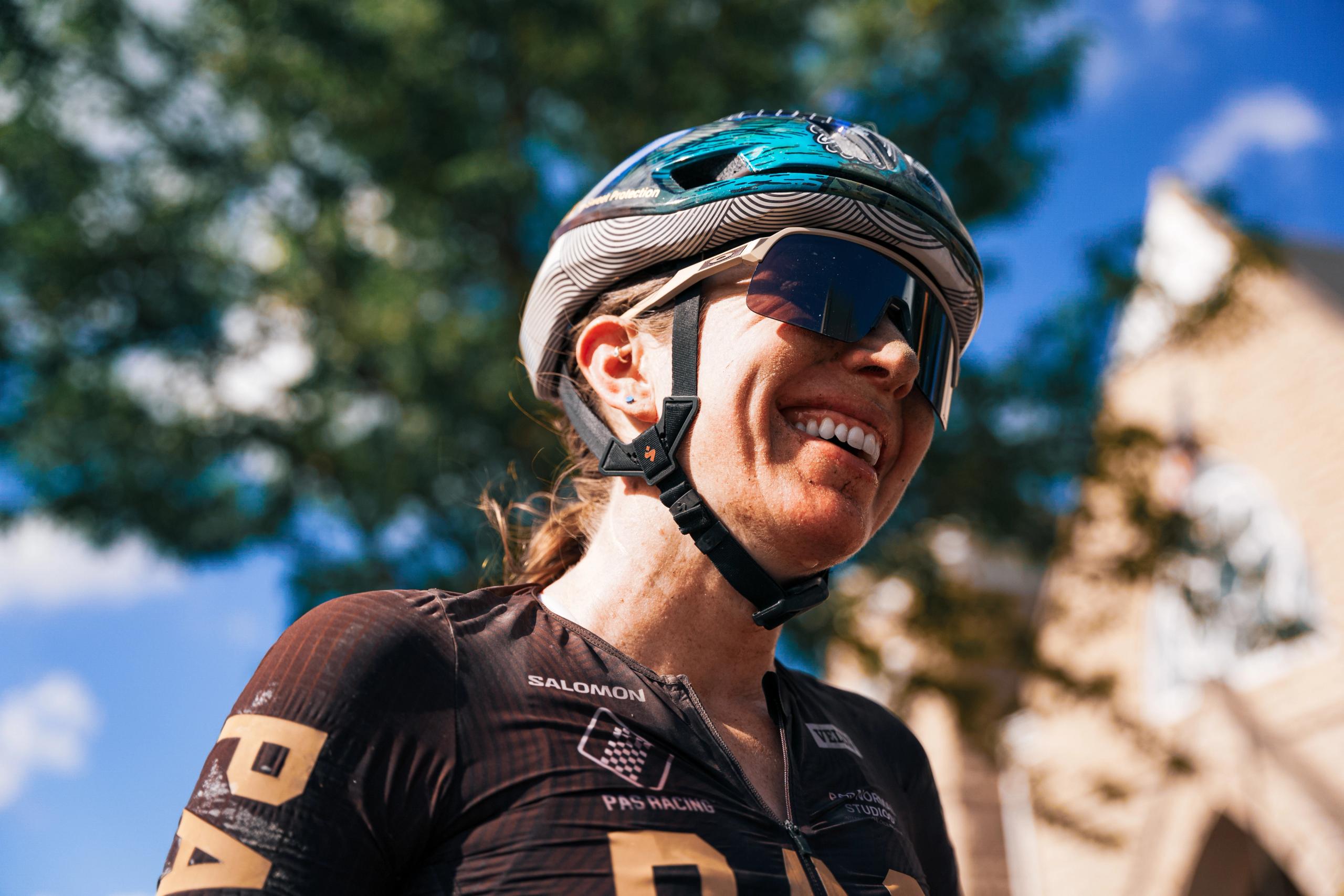Model wearing dark cycling jersey with geometric pattern, helmet and sunglasses outdoors