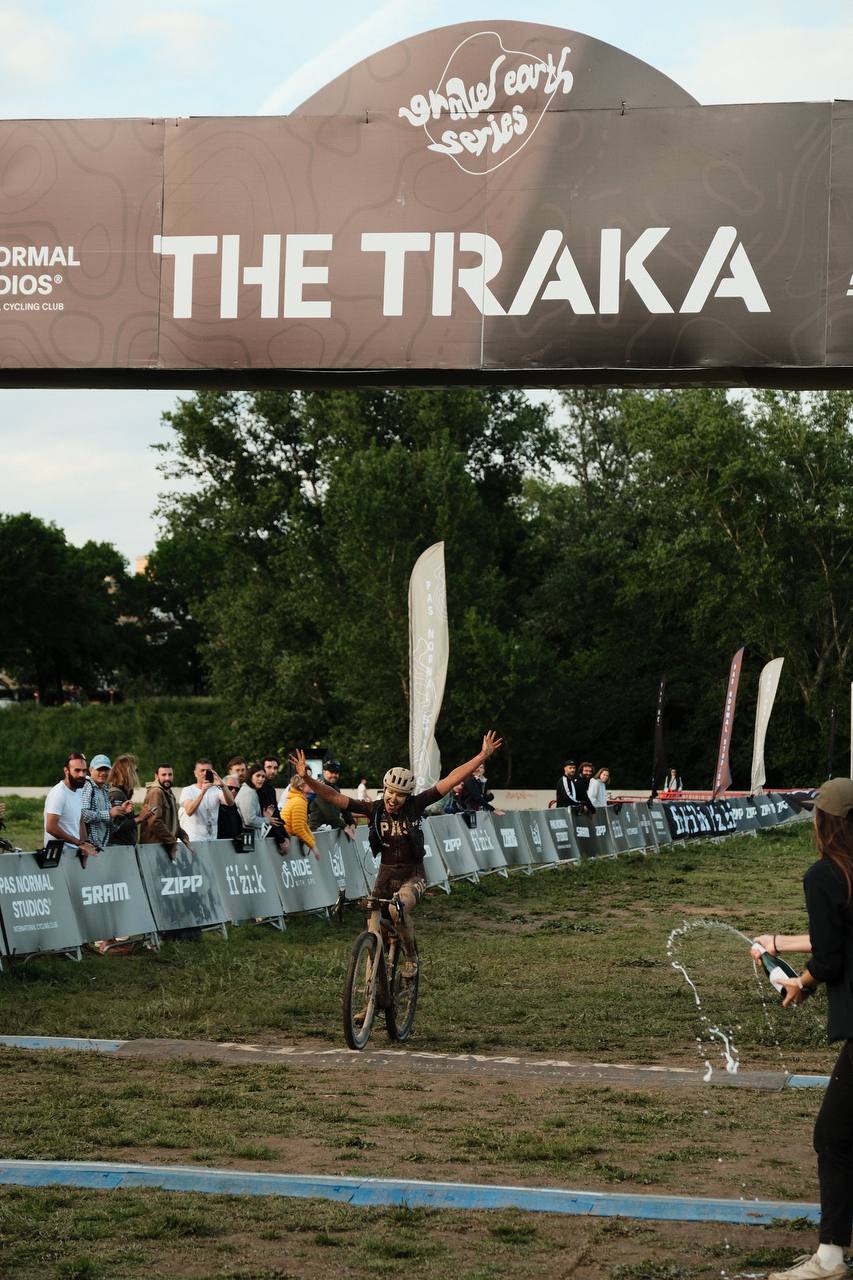 Cyclist celebrating victory at The Traka gravel race finish line with arms raised