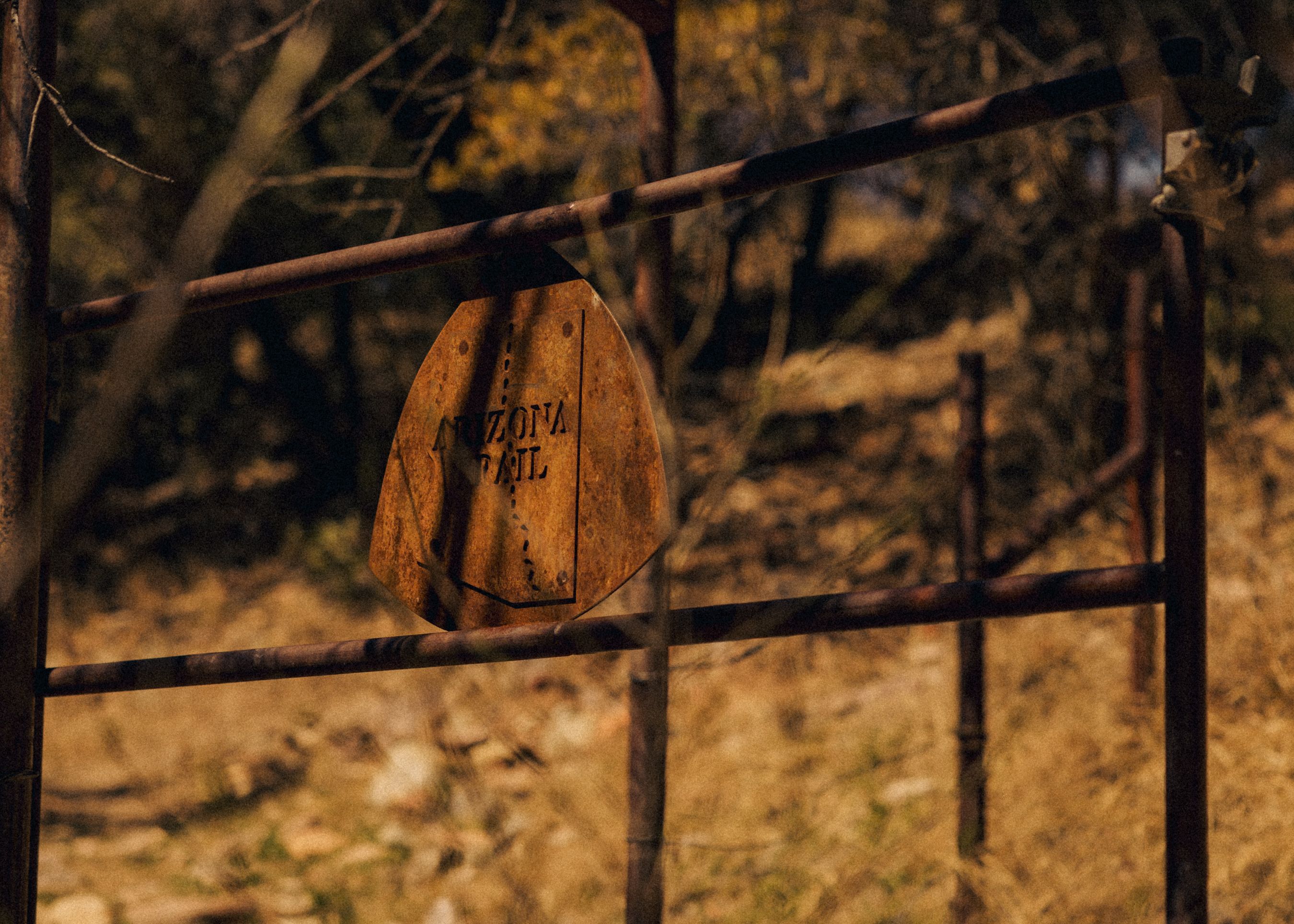Weathered trail marker on metal fence in desert landscape