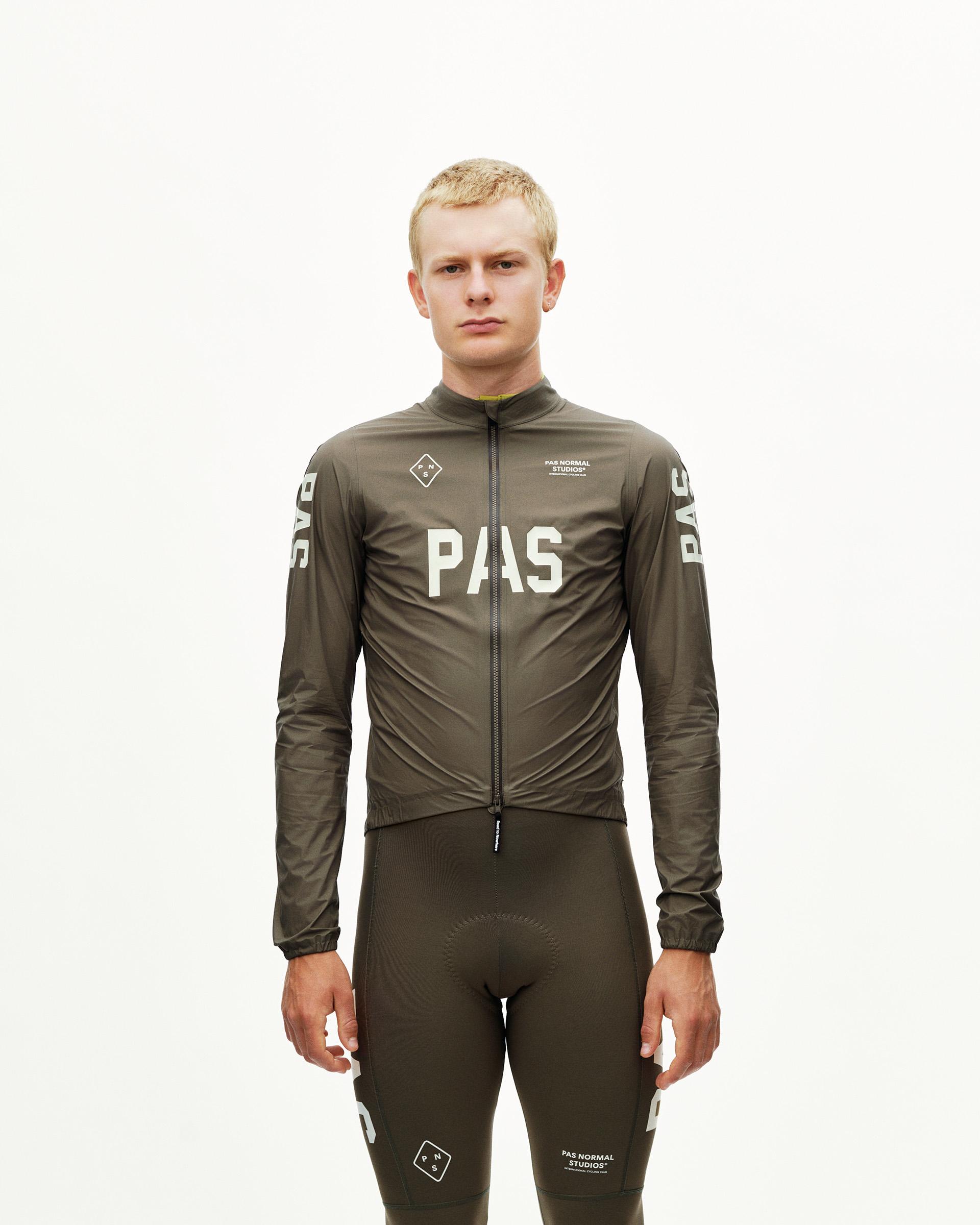 Dark Earth khaki PAS Mechanism cycling rain jacket on model, front view with large chest logo print