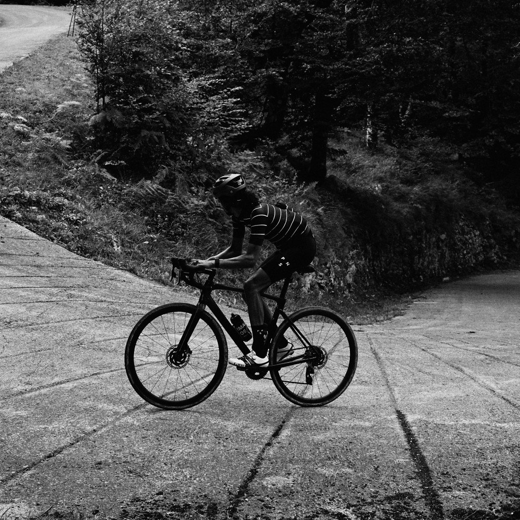Cyclist in striped jersey riding road bike on mountain road in black and white
