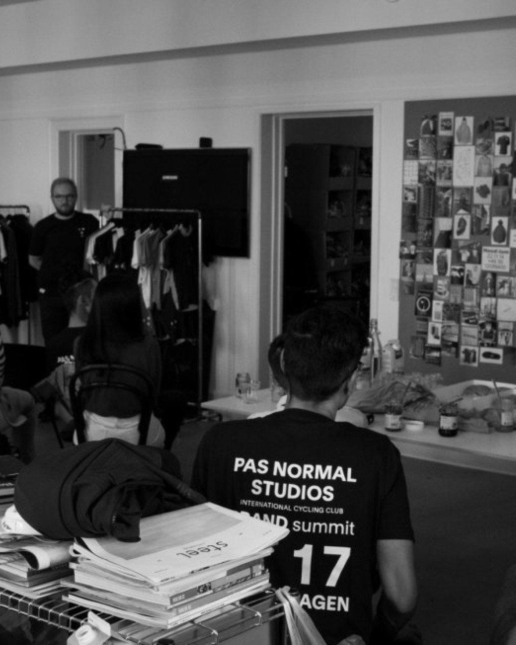 Black and white photo of design studio with person wearing black jersey with logo and text on back