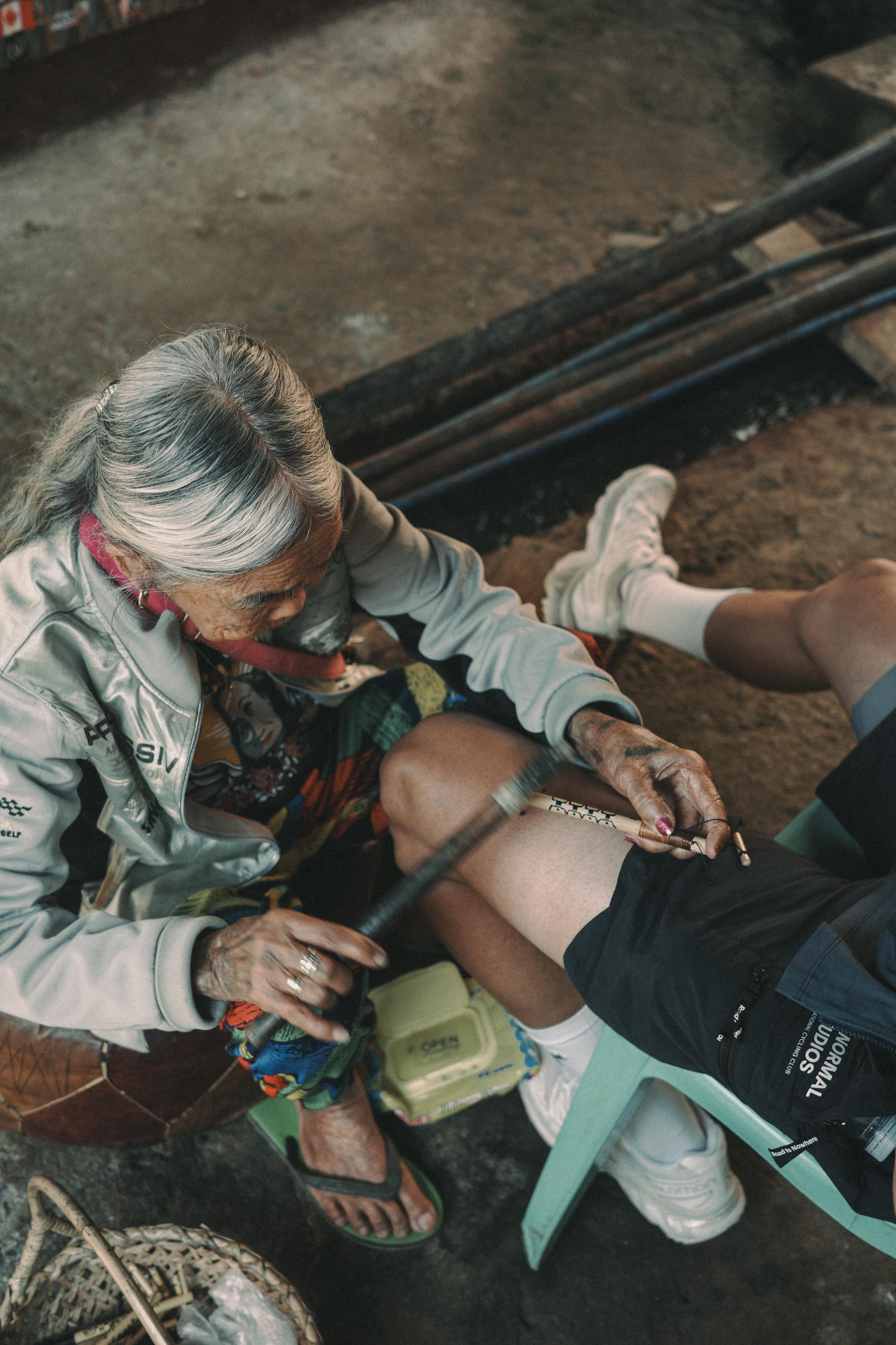 Model wearing grey windbreaker applying leg warmer in cycling preparation scene