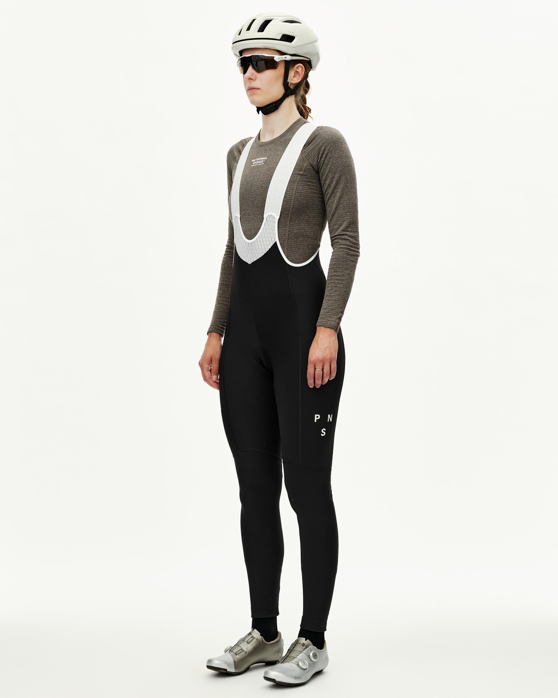 Black Mechanism women's thermal cycling long bibs on model, three-quarter front view with white bib straps