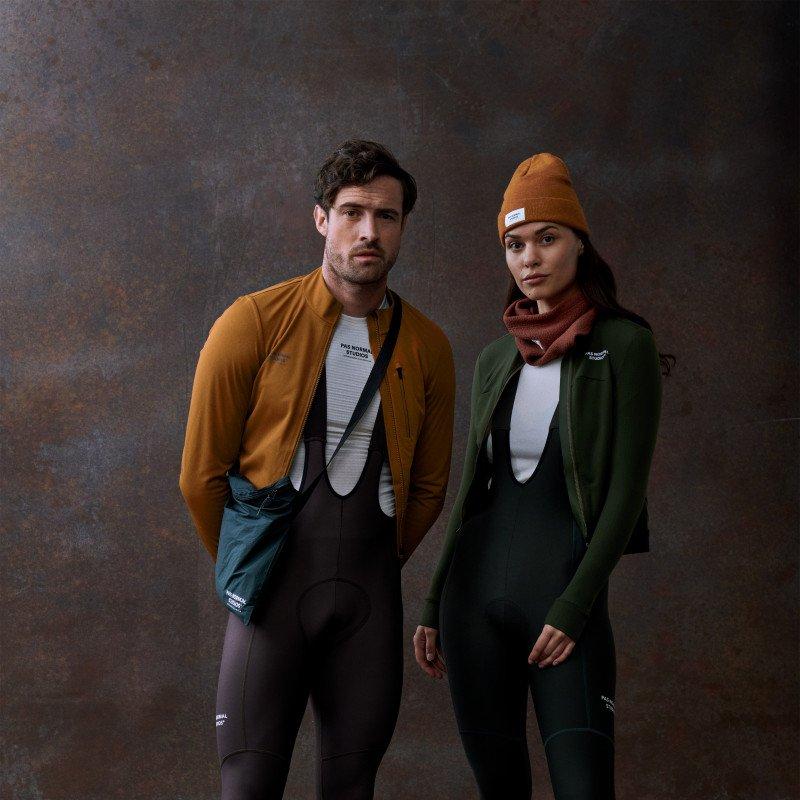 Models wearing Essential collection orange jacket with black bib shorts and green jacket with black bib tights