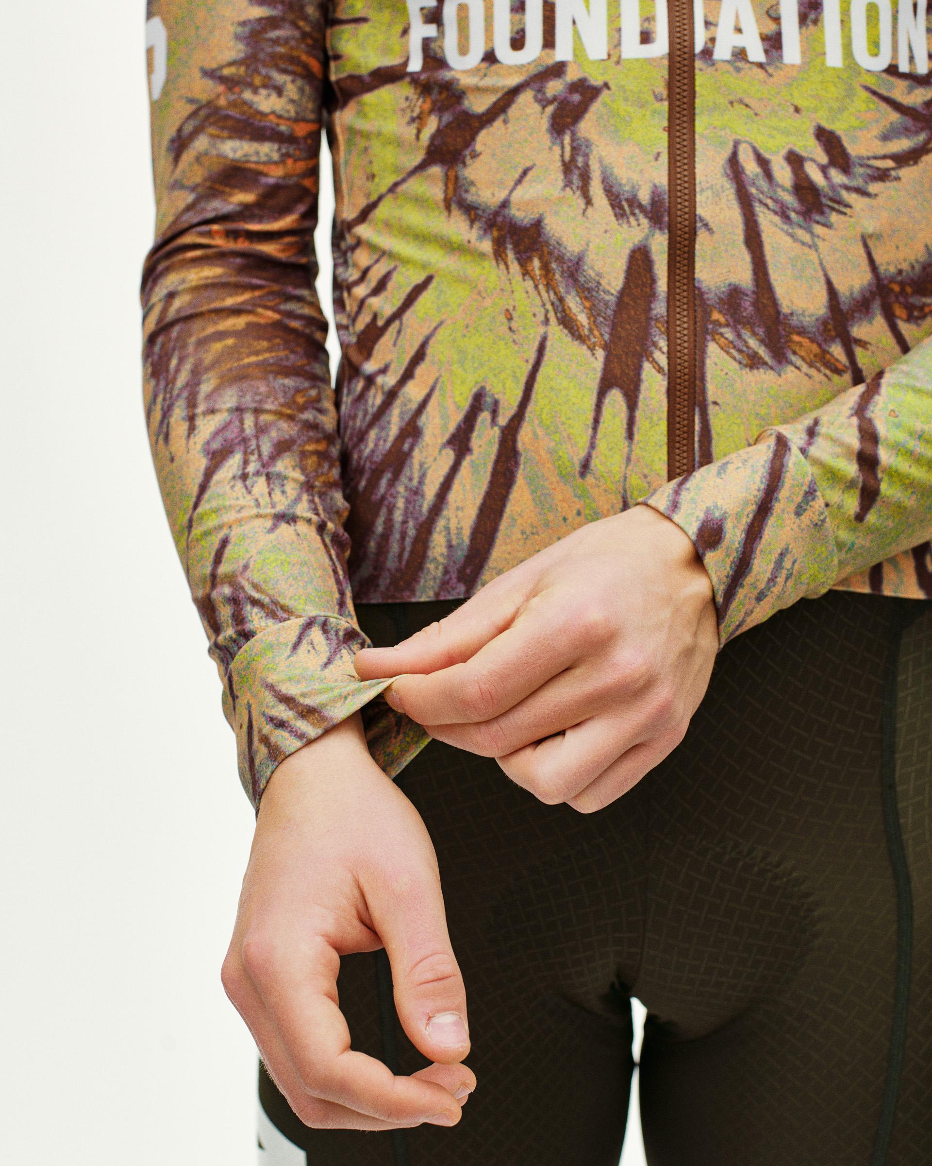 Beige STFR Mechanism long sleeve cycling jersey on model with camouflage print and brown zip