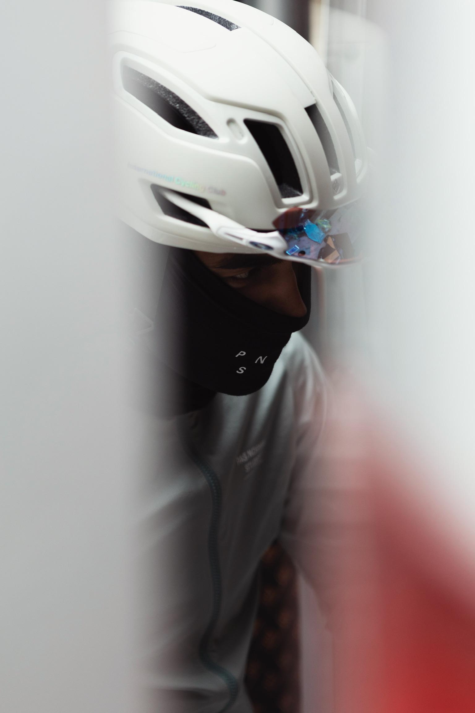 Model wearing white cycling helmet with mirrored visor and black face covering