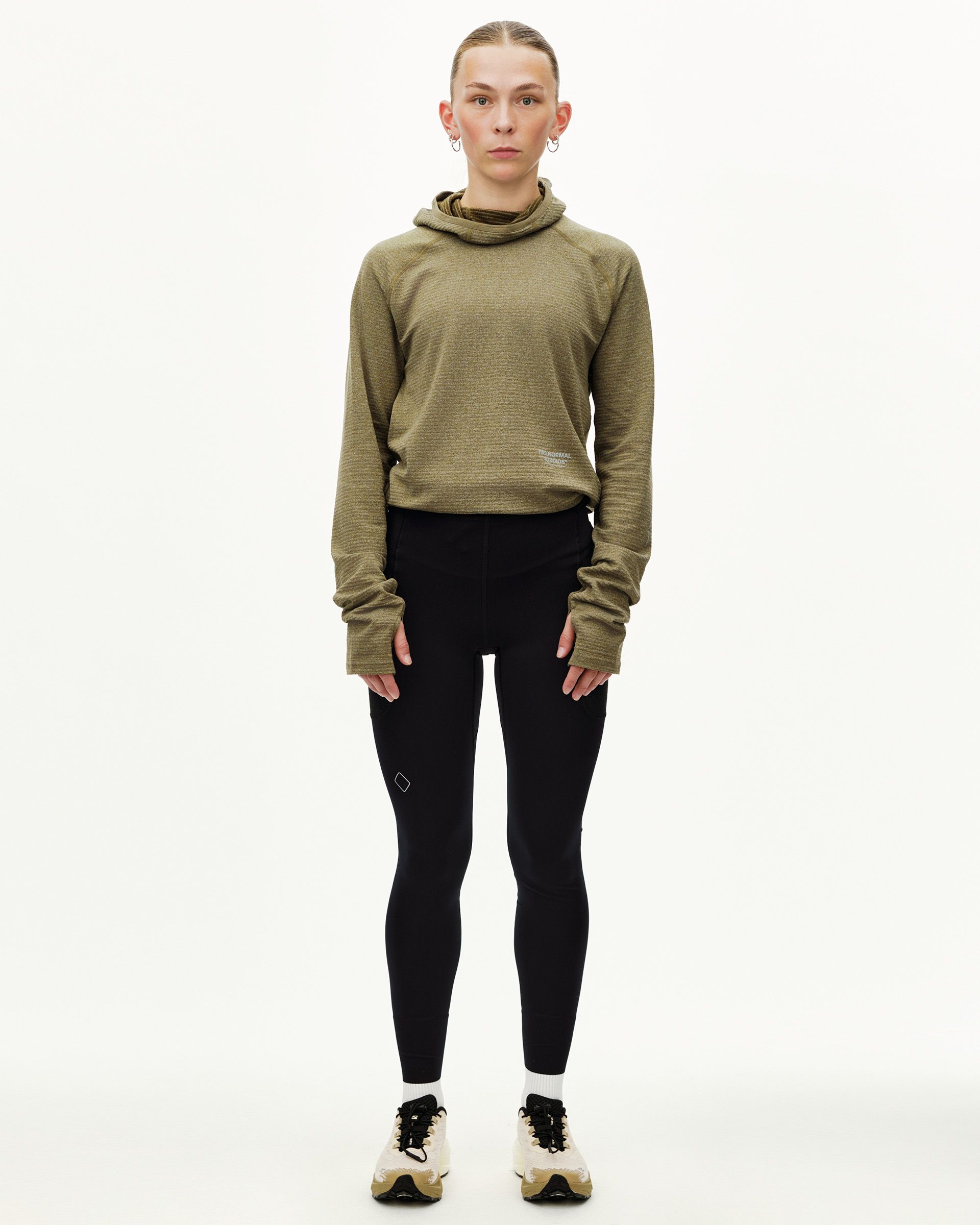 Black Balance long tights on model, front view, worn with olive hooded top
