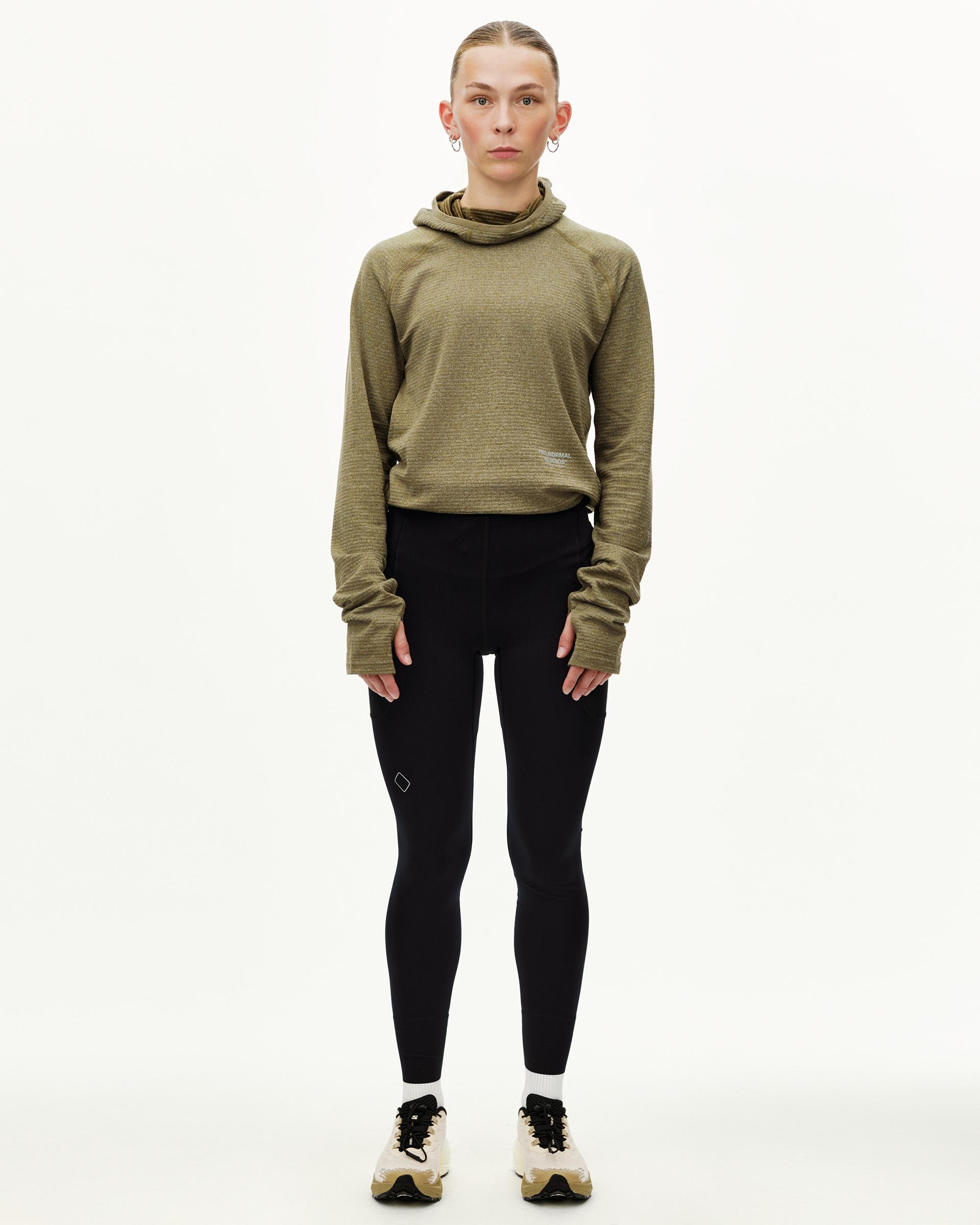 Black Balance long tights on model, front view, worn with olive hooded top