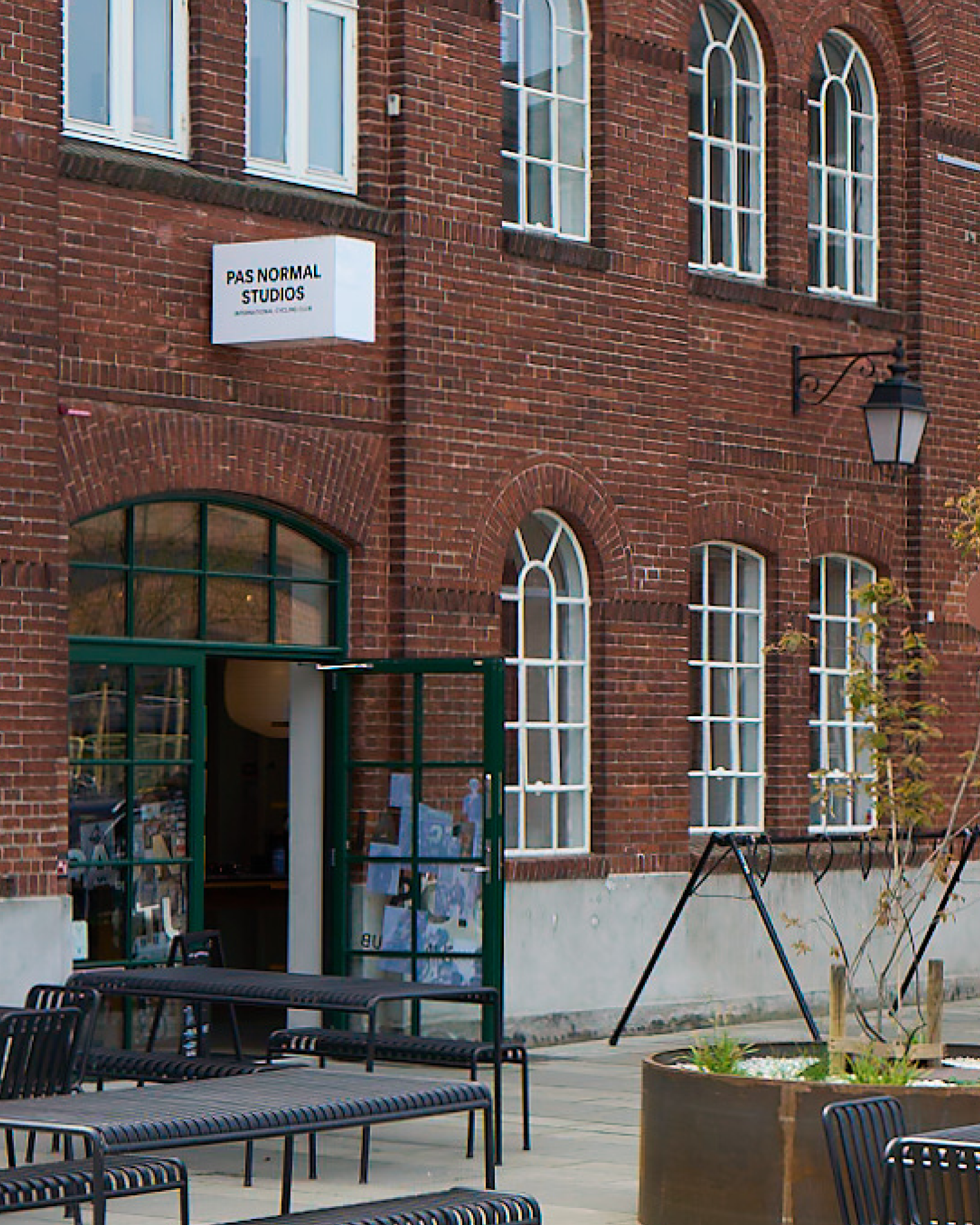 Brand flagship store exterior in Copenhagen with brick facade and green storefront