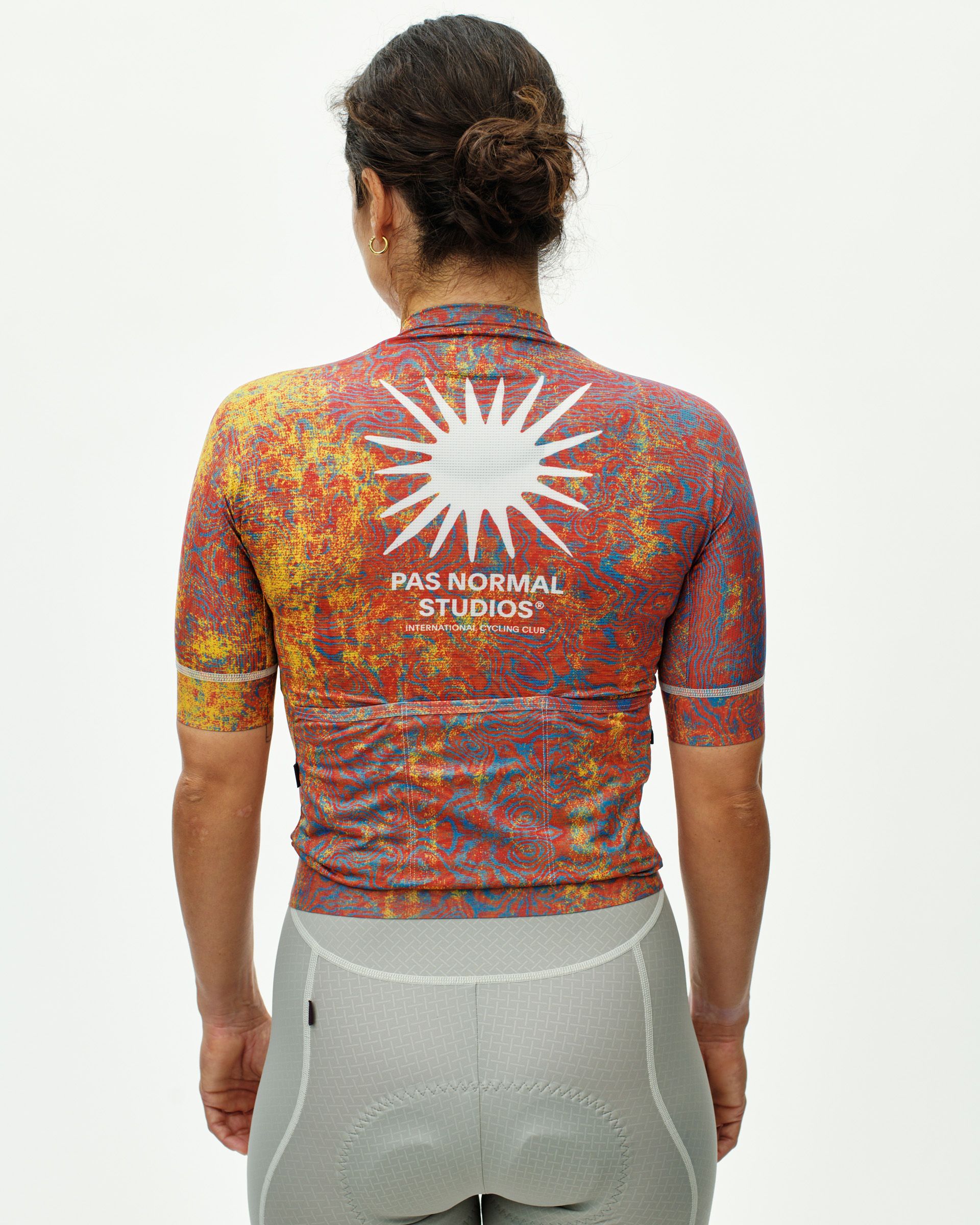 Breakfast Club Mechanism cycling jersey on model, rear view with multicolour terrain print and white sun graphic