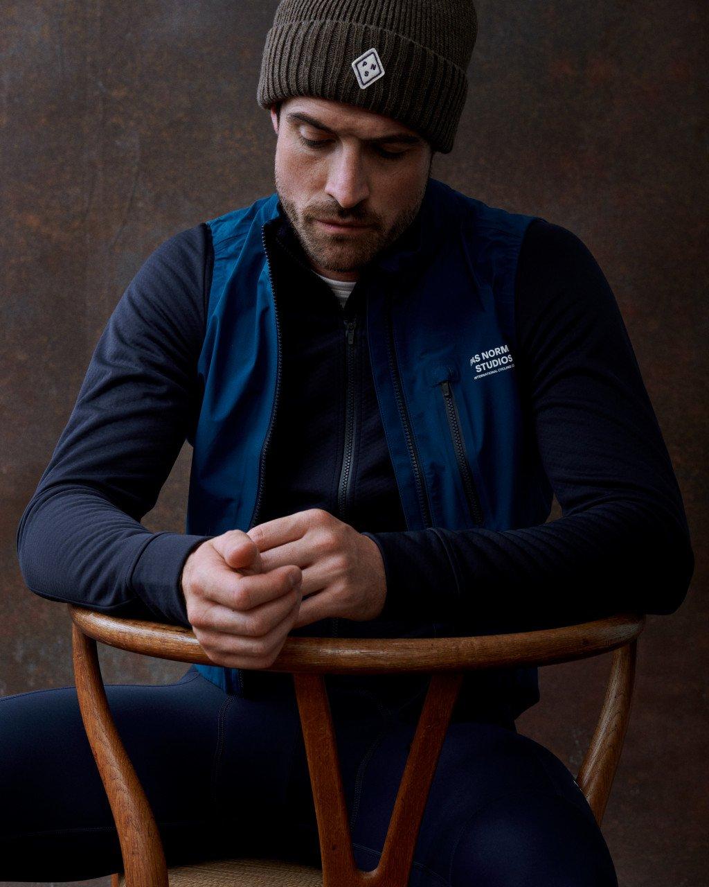 Model wearing Men's Essential bomber jacket in navy blue with logo patch and ribbed knit beanie