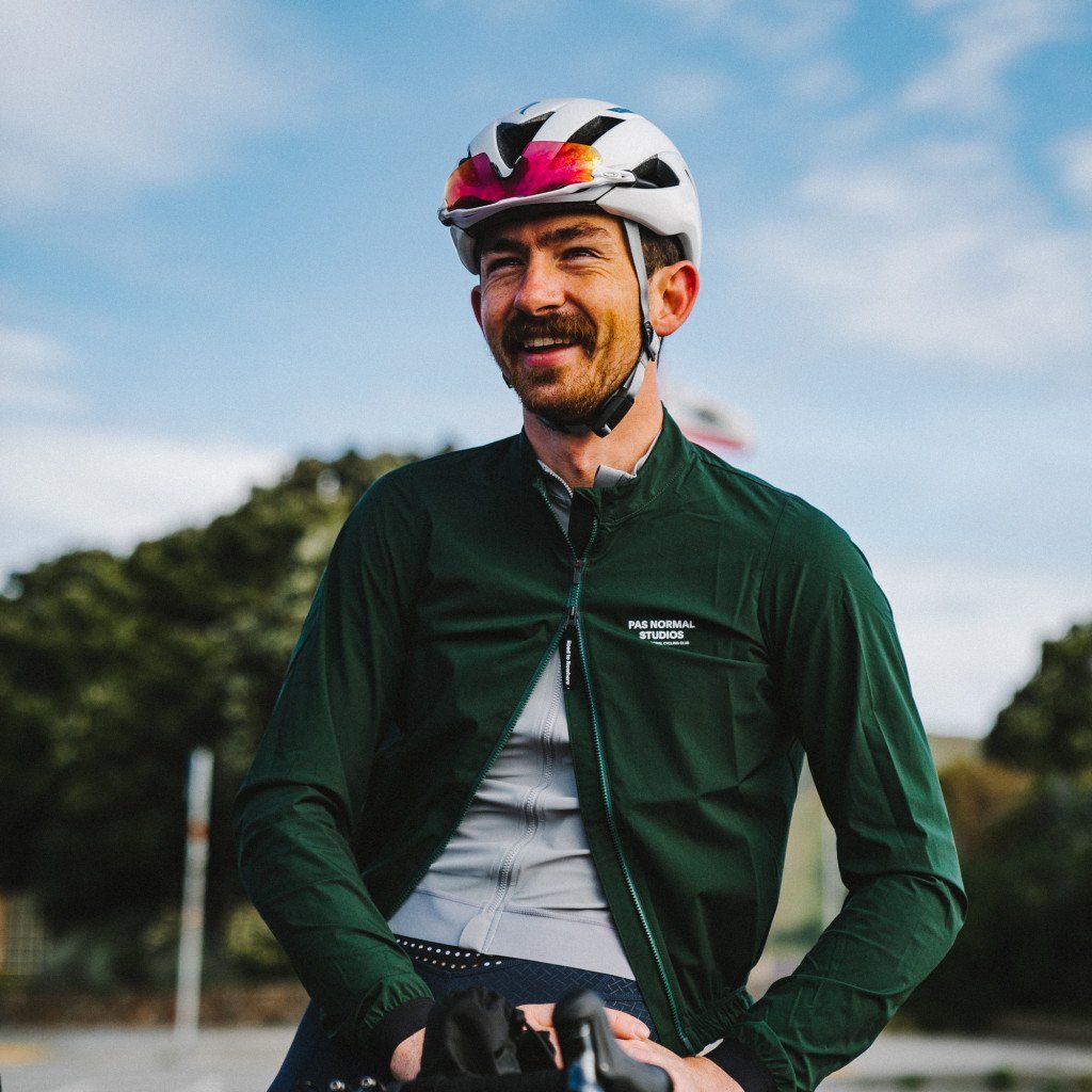 Model wearing green cycling jacket with white helmet and sunglasses outdoors